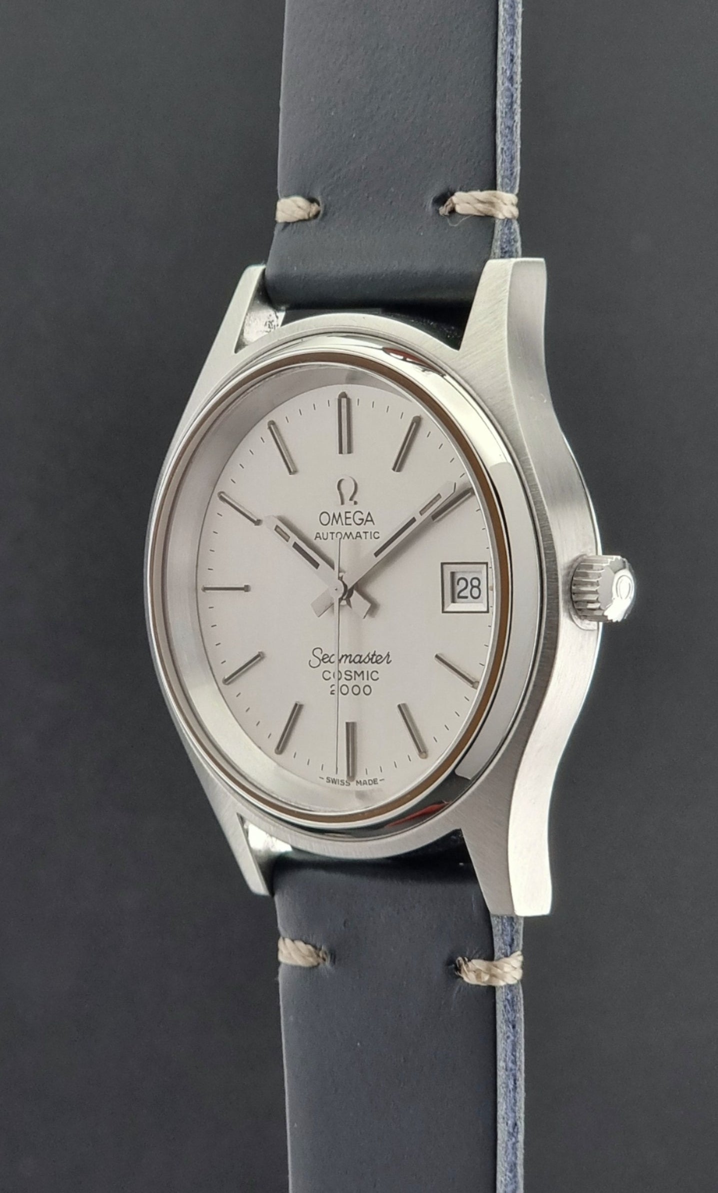 Omega Seamaster Cosmic 2000 166.128 watch with silver dial and blue strap on a dark background