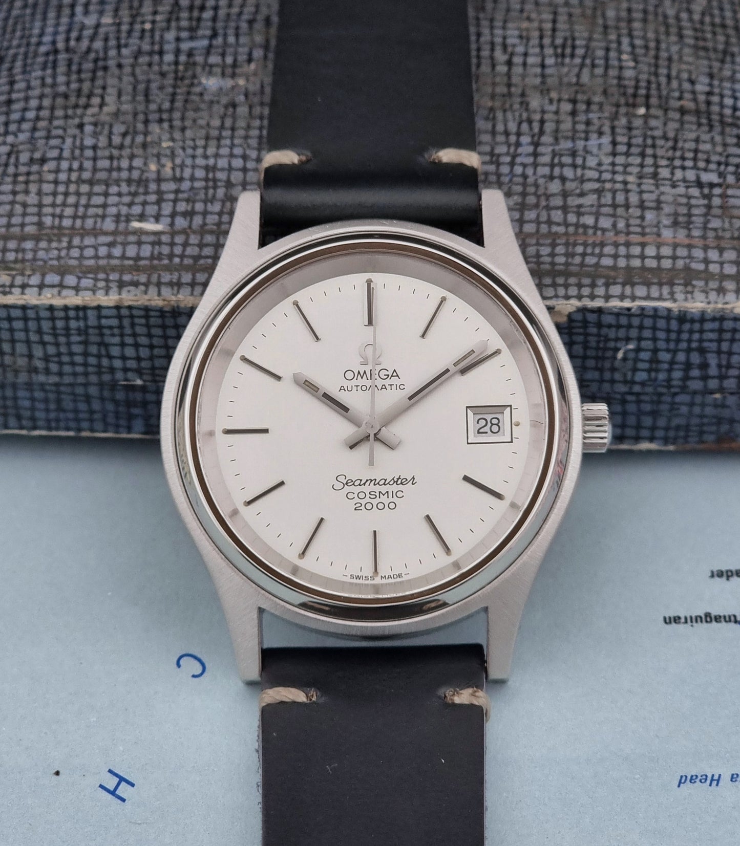Omega Seamaster Cosmic 2000 166.128 Seamaster watch with black strap on a textured surface