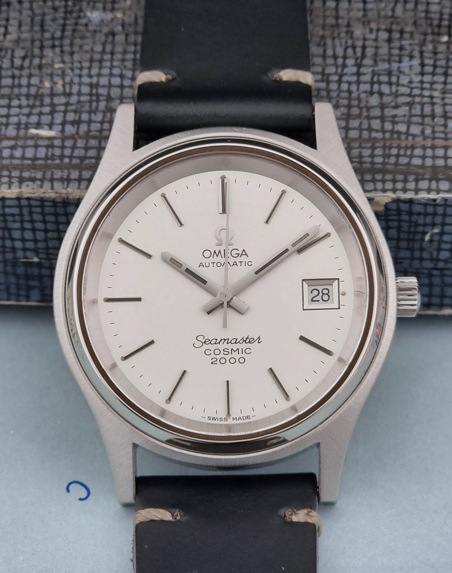 Omega Seamaster Cosmic 2000 166.128 vintage watch with black strap on a textured surface