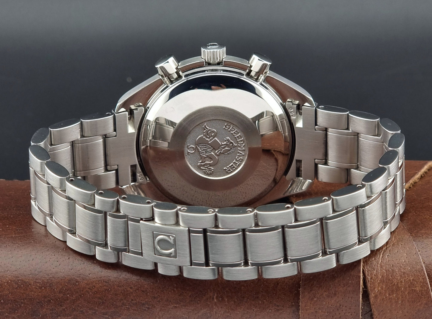 Omega Speedmaster watch with a detailed back cover on a brown surface