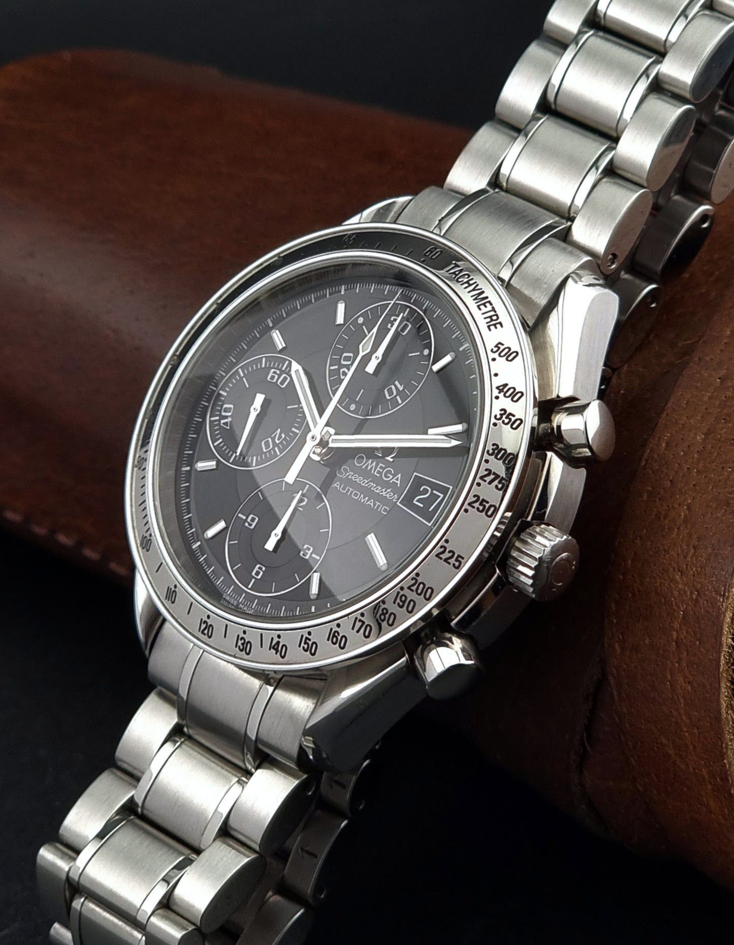 Omega Speedmaster watch with a detailed face on a brown leather surface