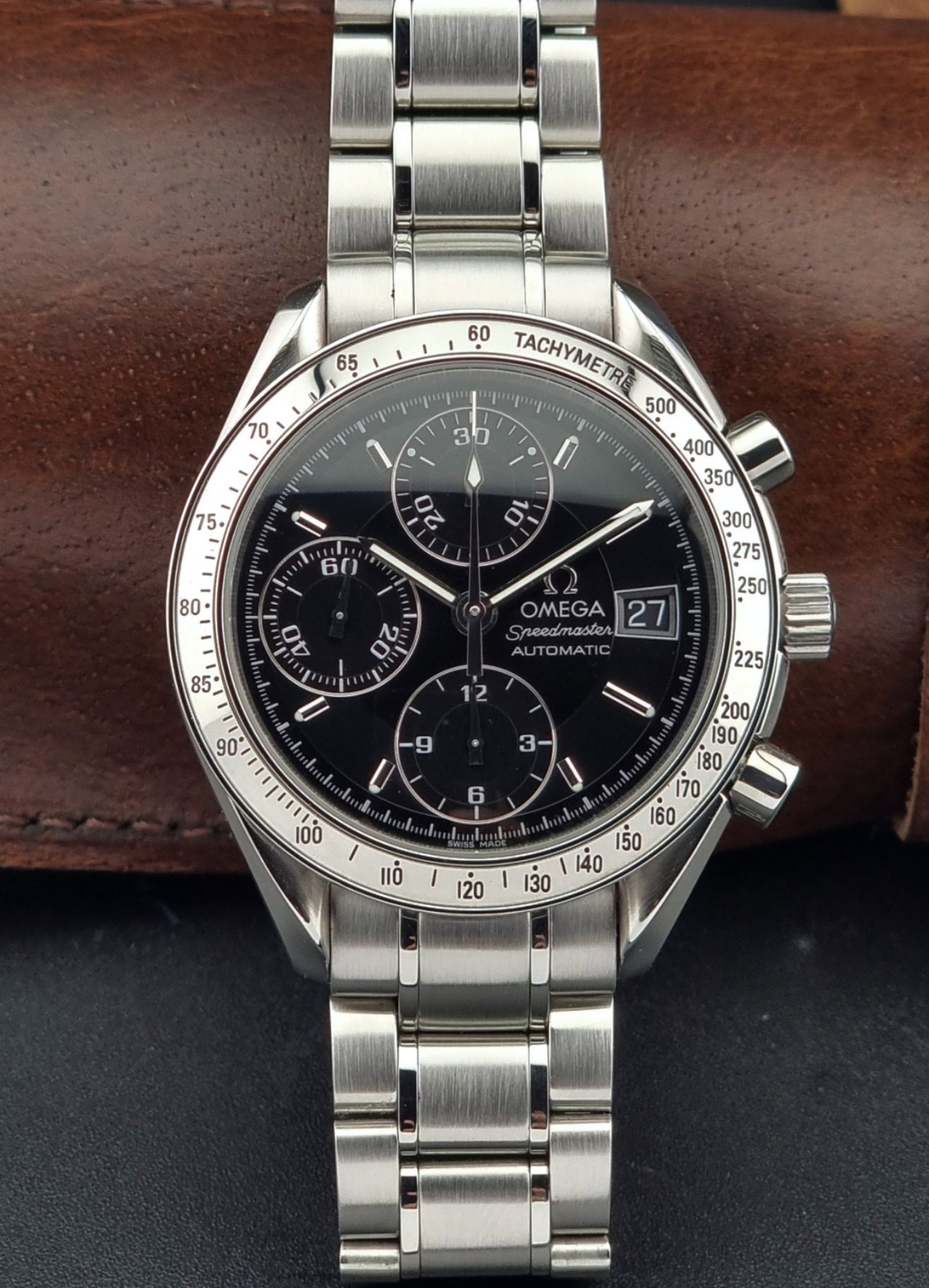 Omega Speedmaster watch with black dial on a brown leather strap