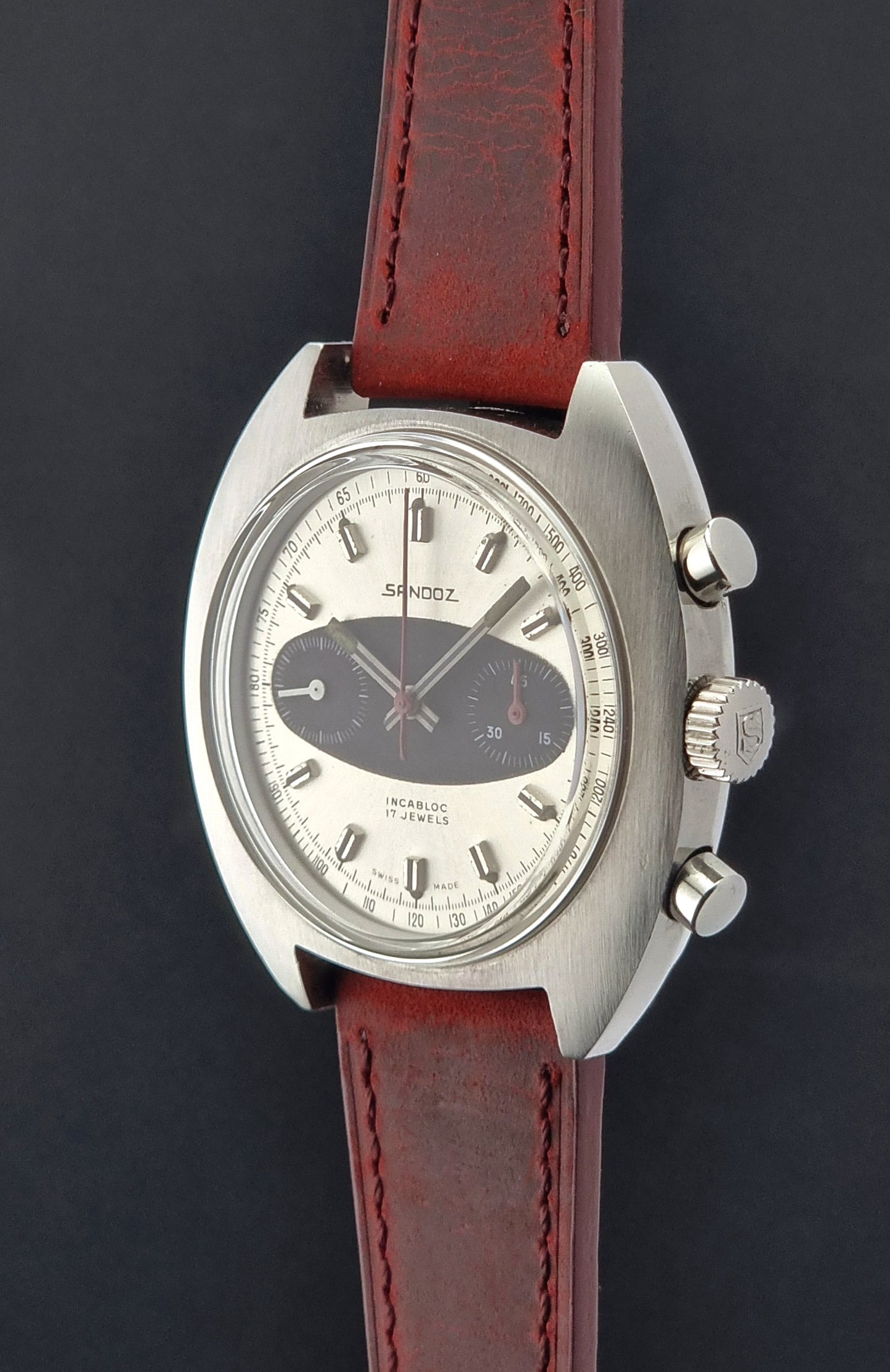 Wristwatch with red leather strap and silver case on a dark background