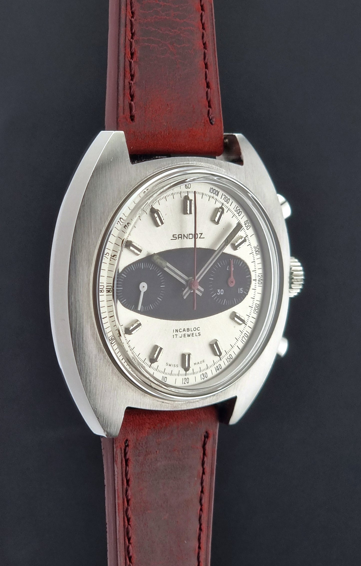 Vintage watch with a red leather strap on a dark background