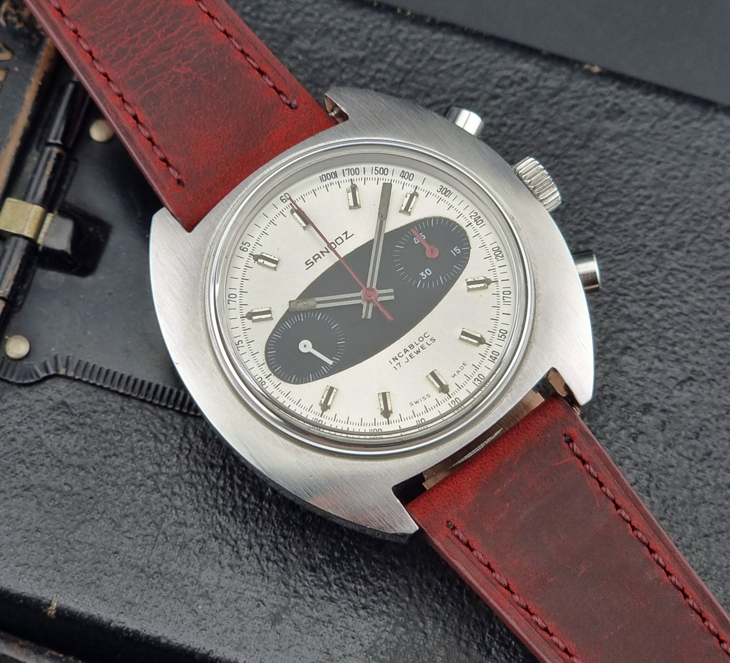 Vintage watch with red leather strap on a dark textured background