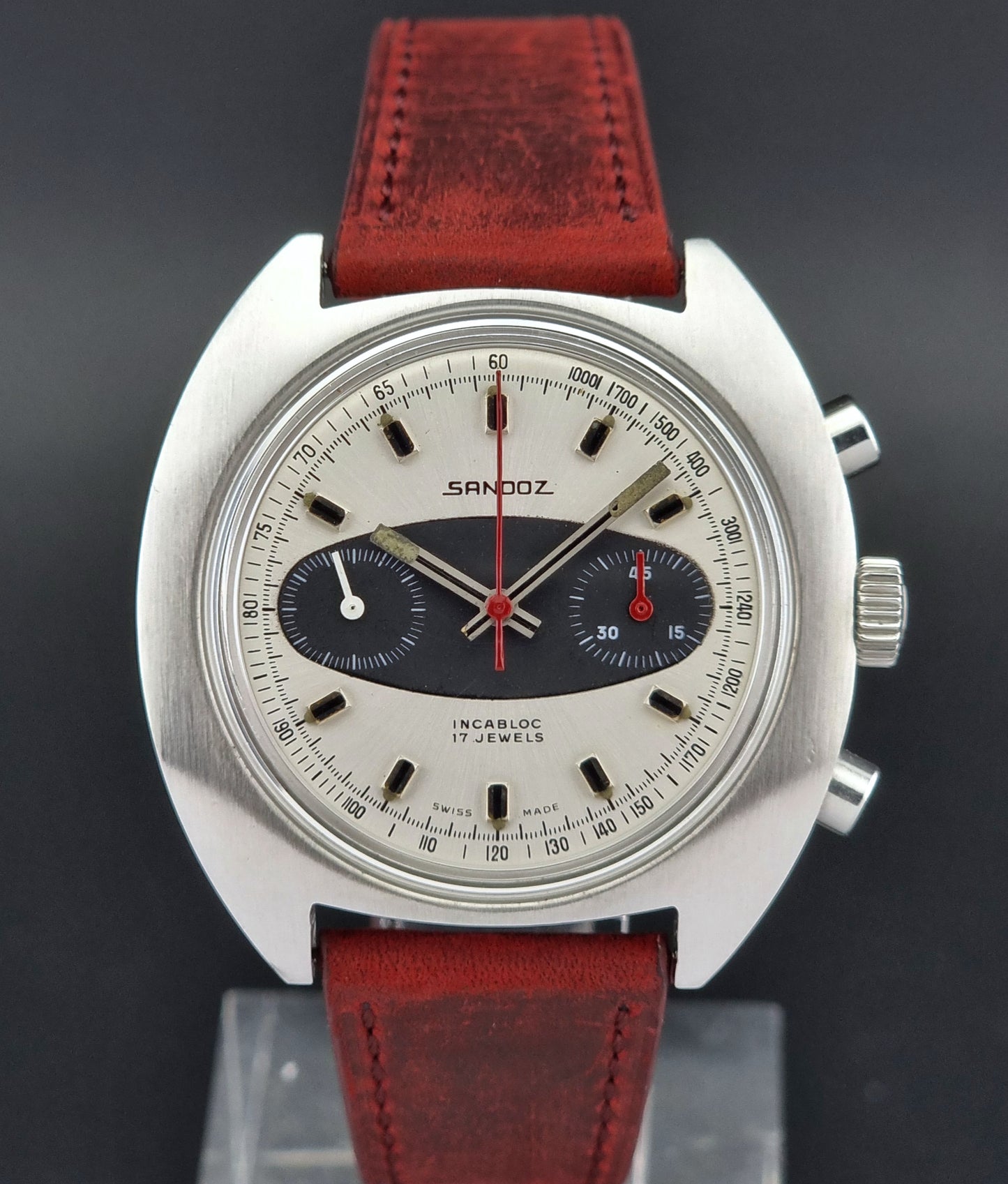 Vintage Sandoz wristwatch with red leather strap on a dark background