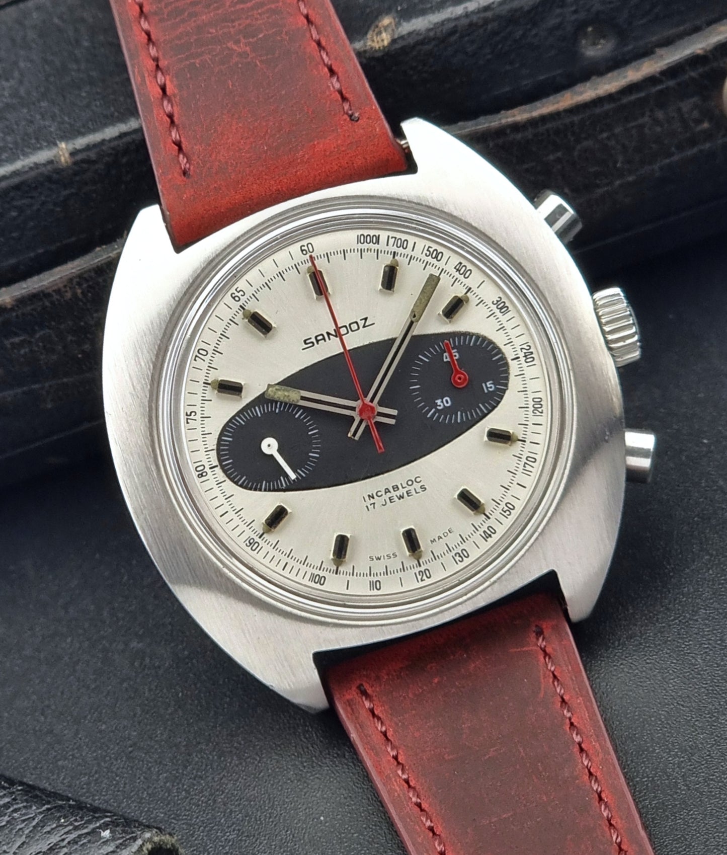 Vintage watch with red leather strap on a dark textured background