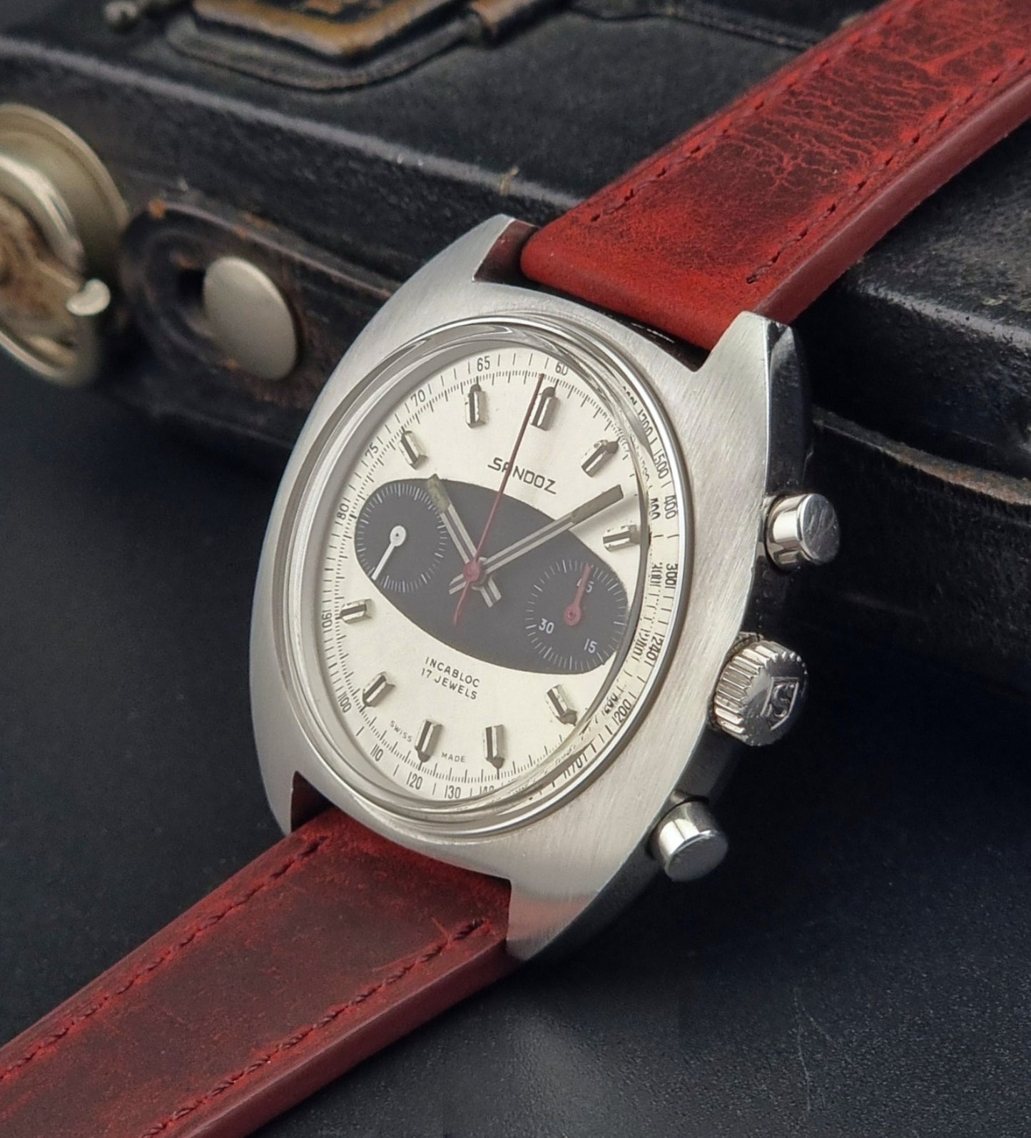 Vintage Sandoz watch with red leather strap on a dark textured background