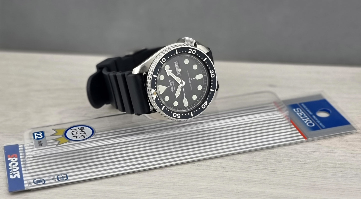Seiko watch with black strap and packaging on a gray surface