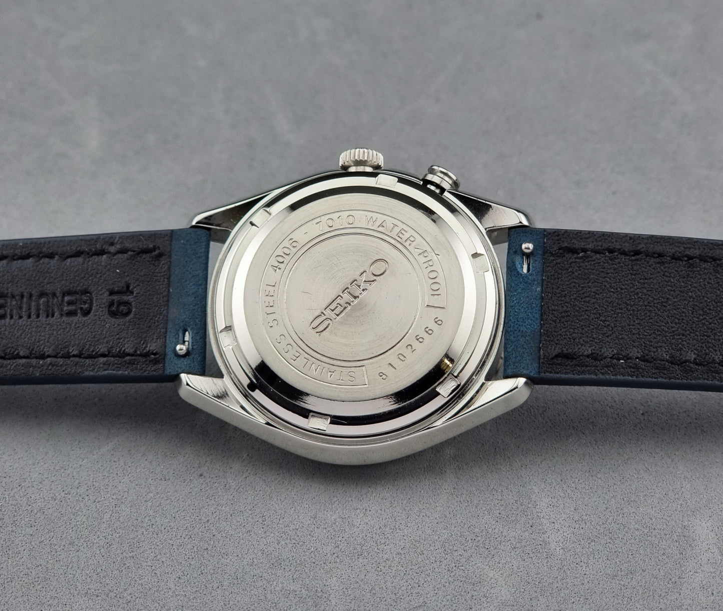 Vintage Seiko Alarm Watch Bell-Matic 4006-7010 with a blue strap on a grey background case back side