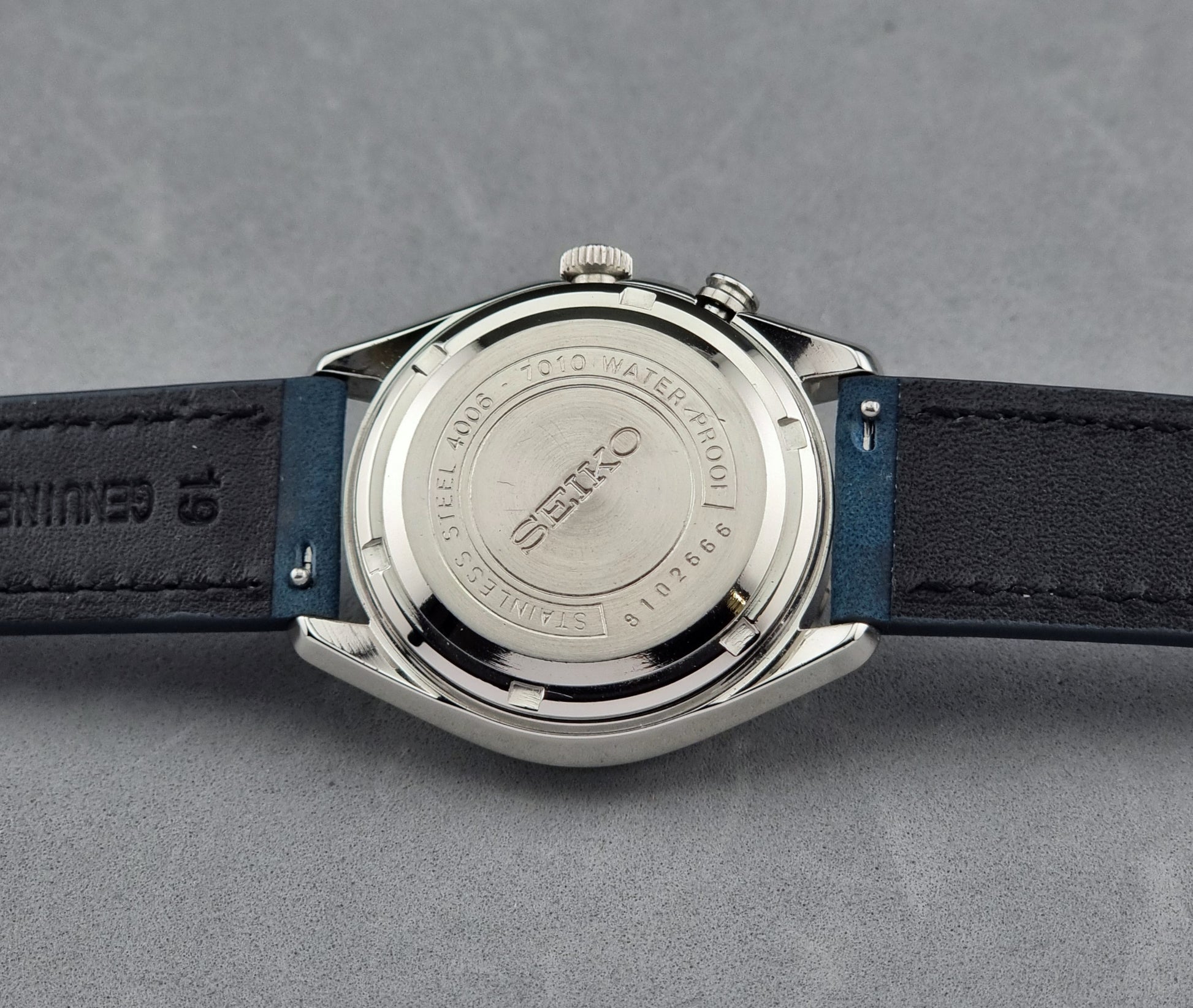Vintage Seiko Alarm Watch Bell-Matic 4006-7010 with a blue strap on a grey background case back side