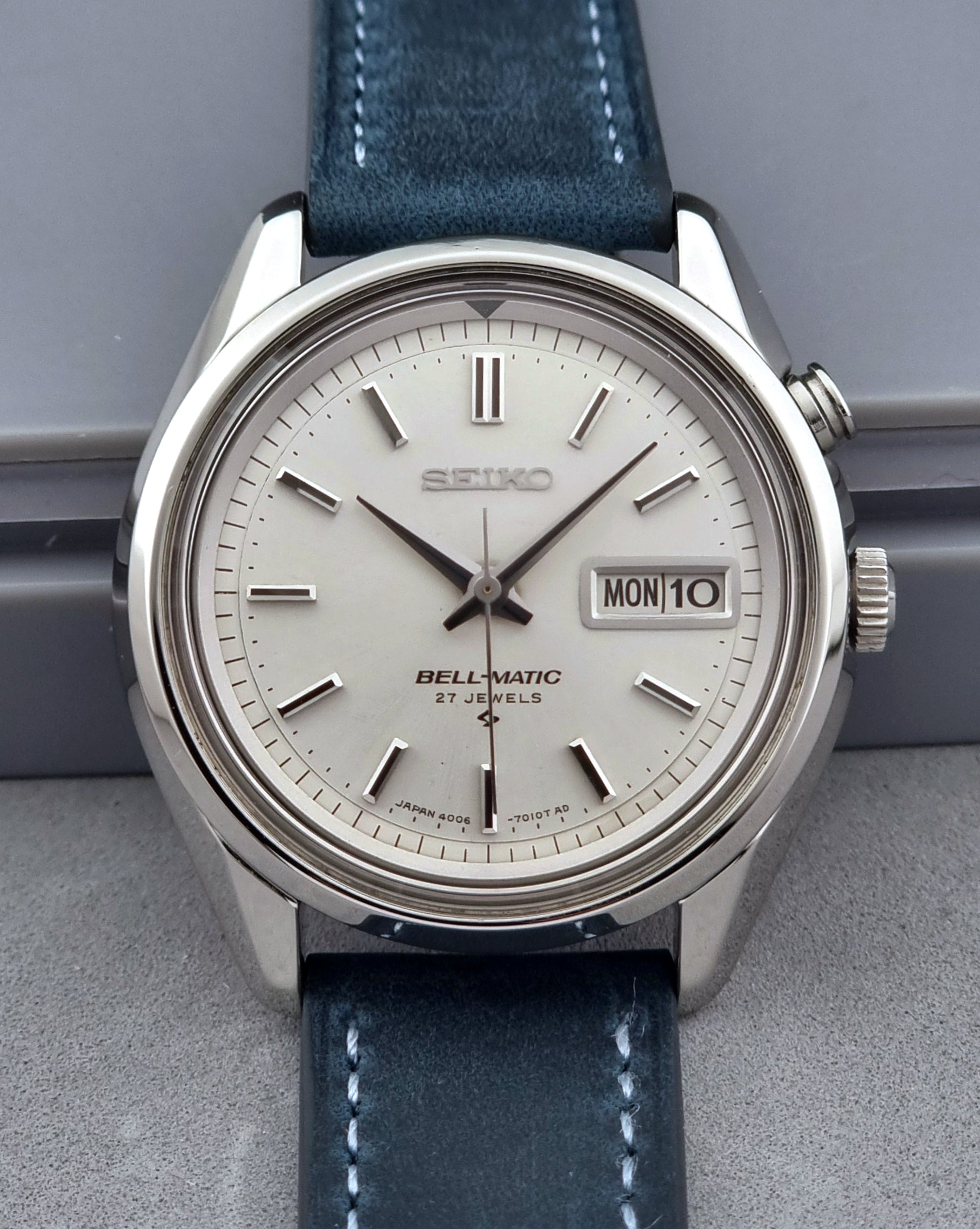 Vintage Seiko Alarm Watch Bell-Matic 4006-7010 with a blue strap on a grey background close up of the dial