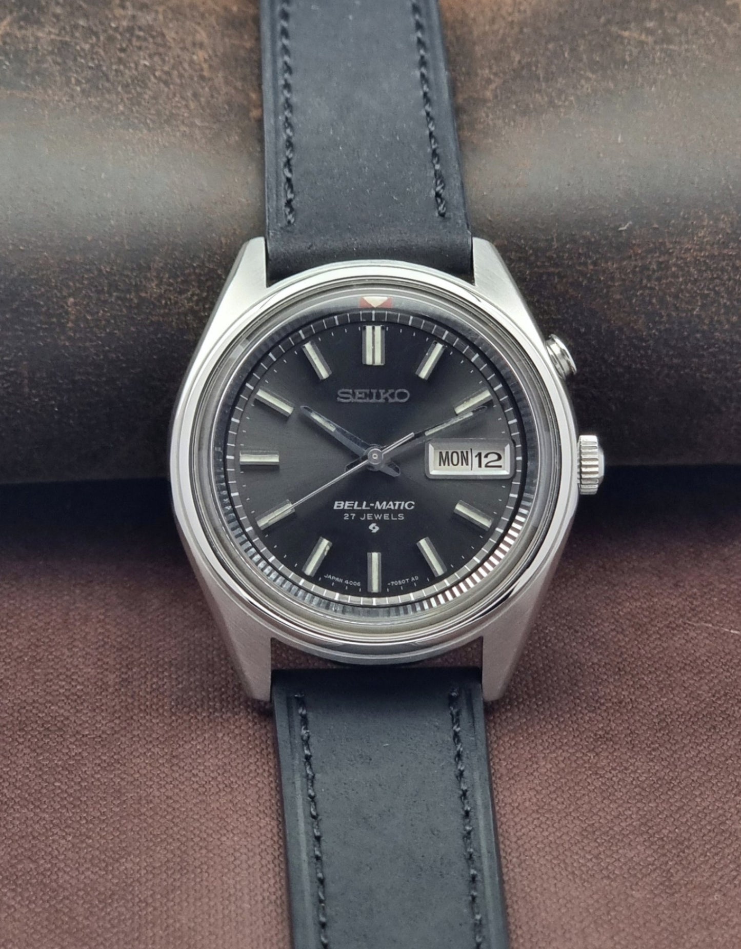 Vintage Seiko Bell-Matic watch with black leather strap on a brown background