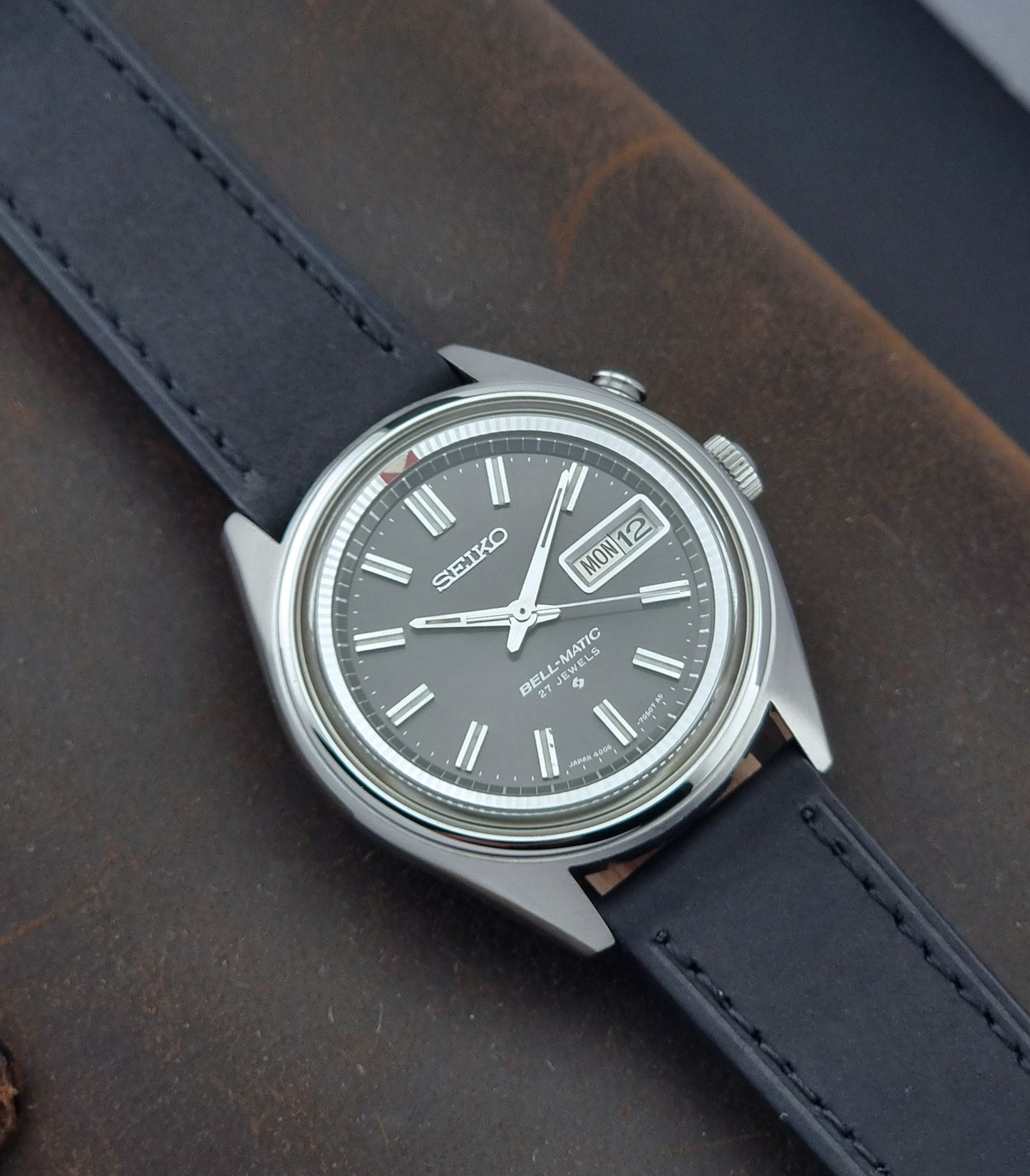 Vintage Seiko Bell-Matic watch with black leather strap on a textured surface