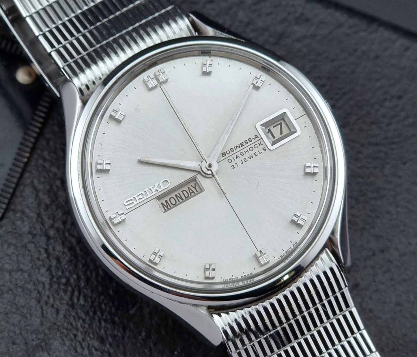 Silver Seiko watch with a detailed face on a dark textured background