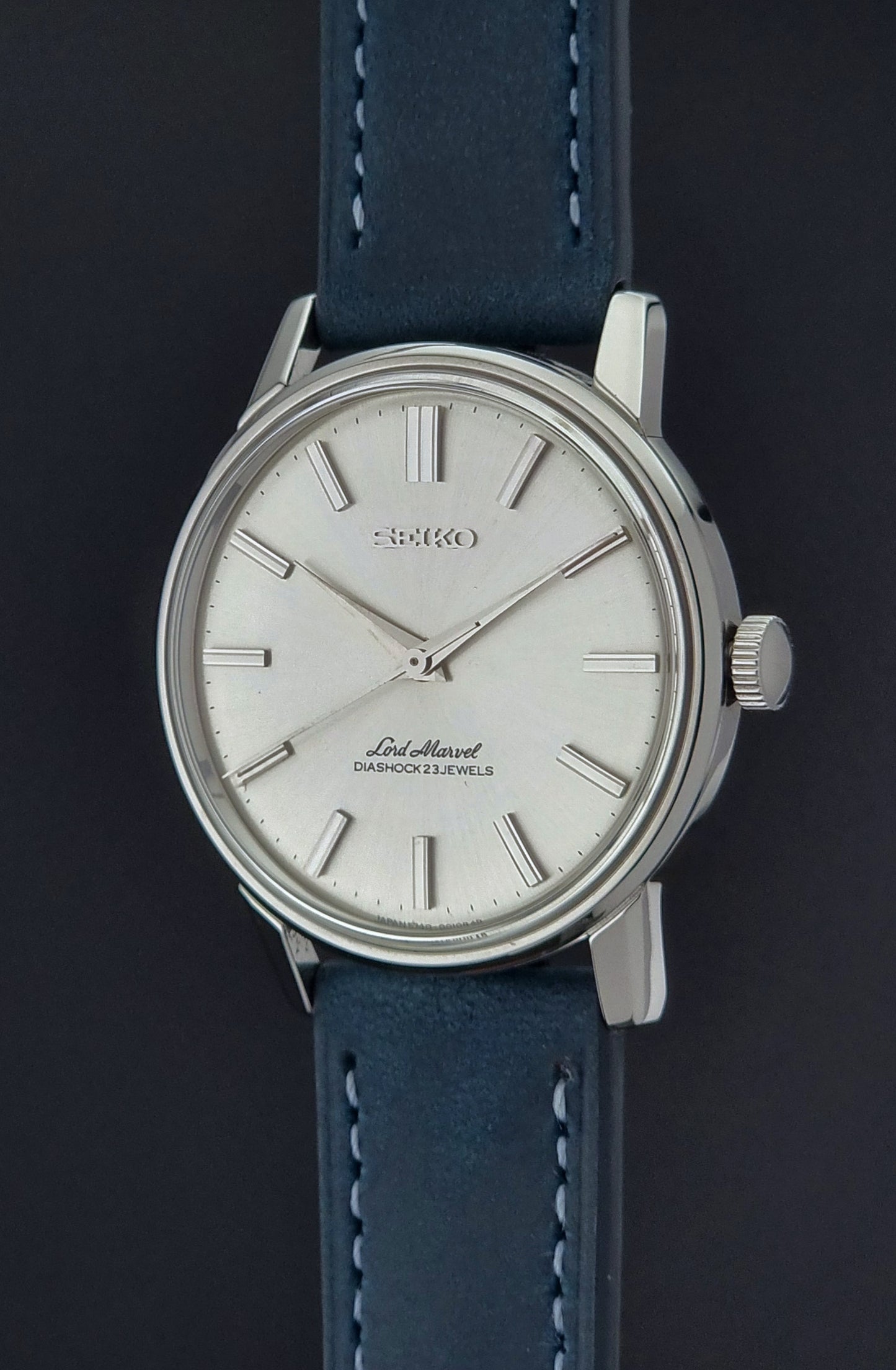 Vintage Seiko Lord Marvel wristwatch with blue leather strap and silver case on a dark background