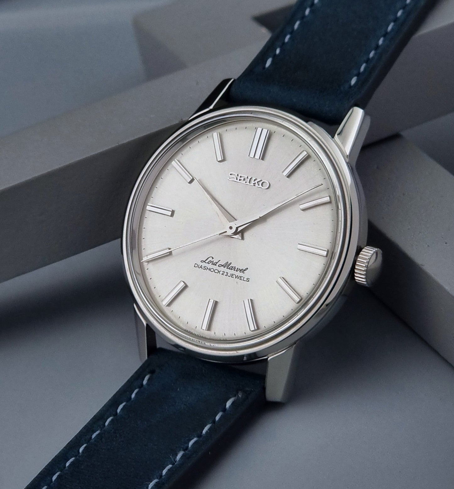 Seiko watch with blue strap on a gray surface