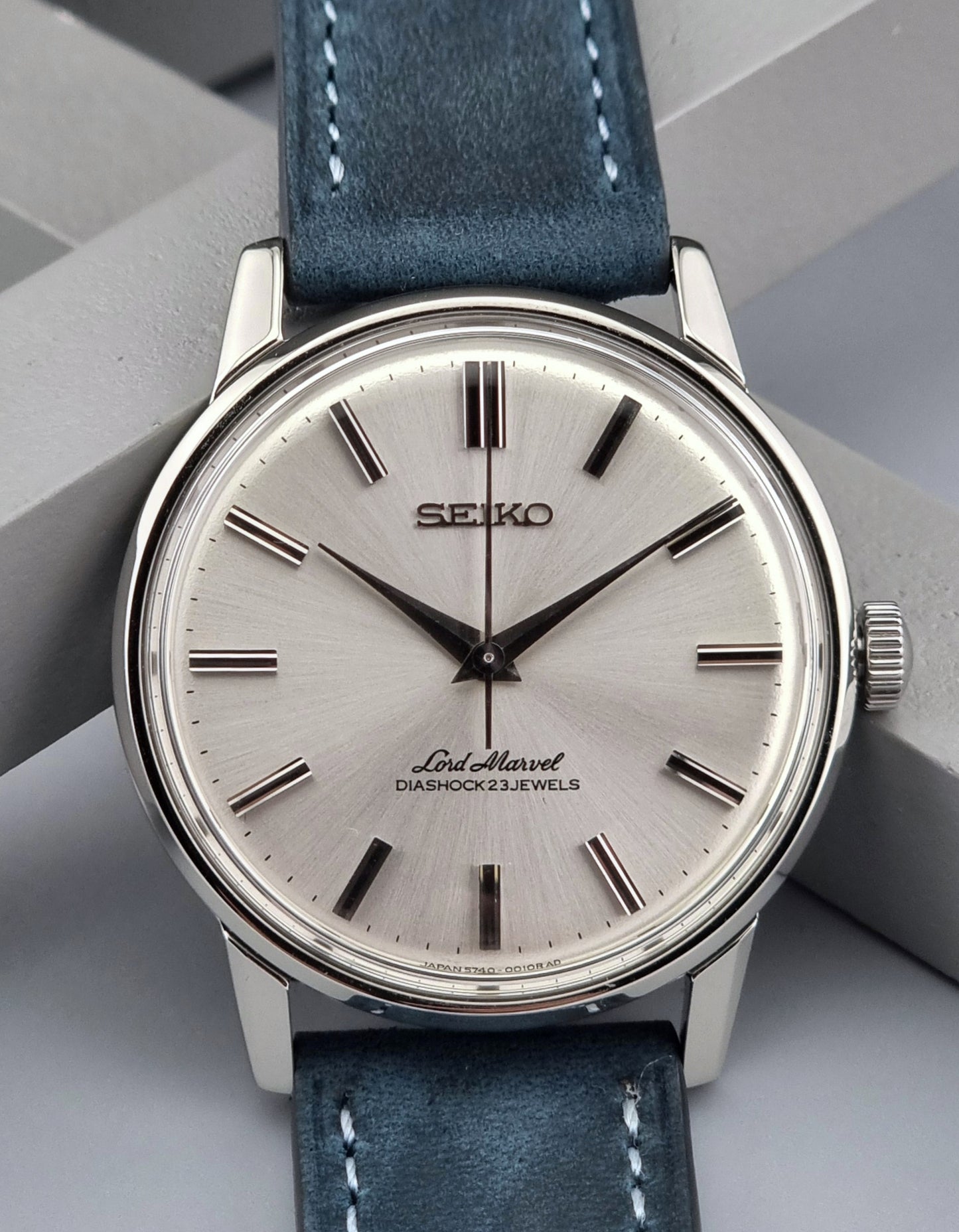 Vintage Seiko Lord Marvel wristwatch with blue leather strap on a gray background