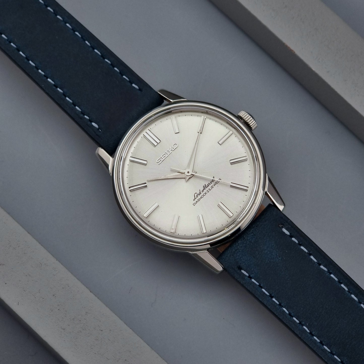 Vintage Seiko Lord Marvel wristwatch with blue strap on a gray surface