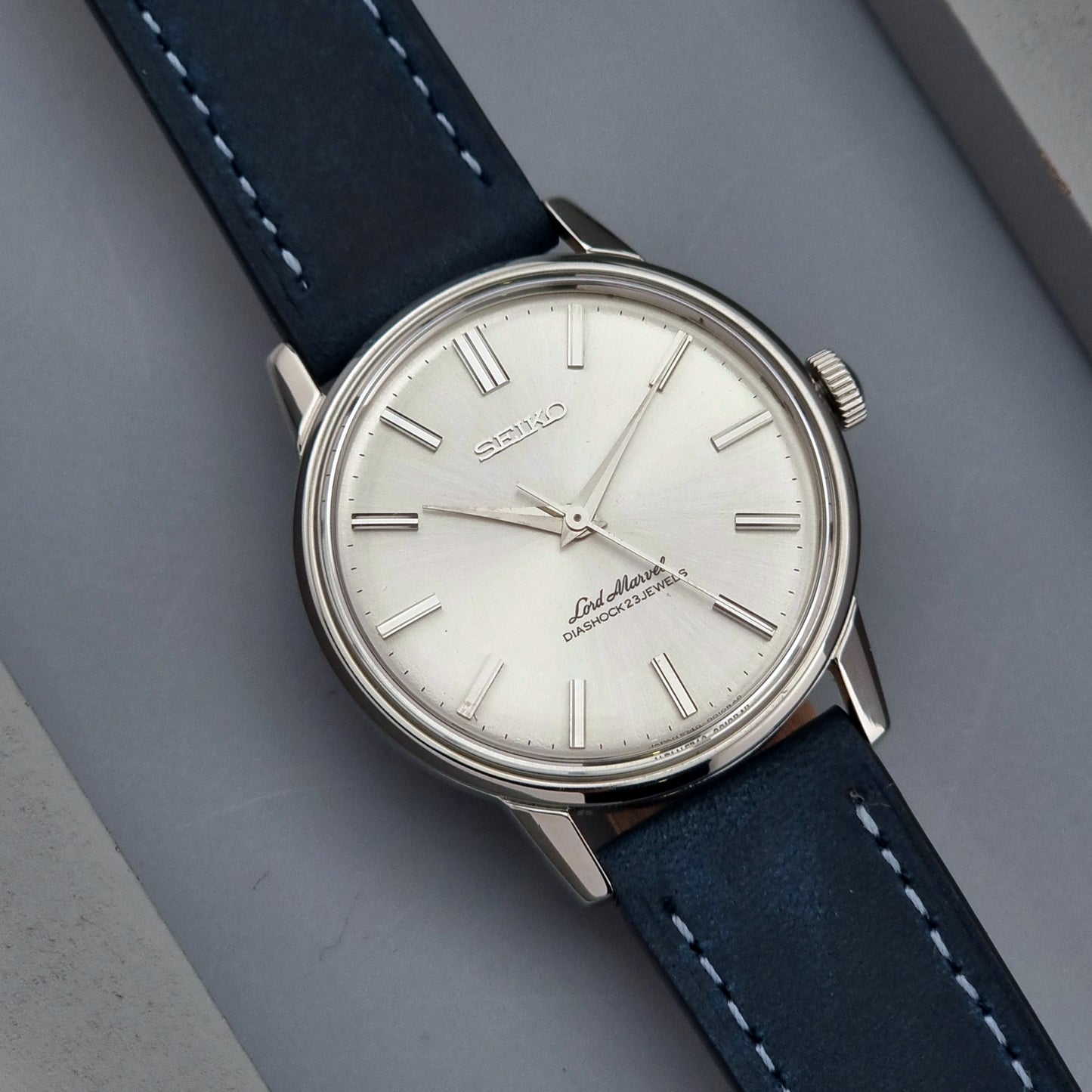 Vintage Seiko Lord Marvel wristwatch with blue leather strap on a gray background