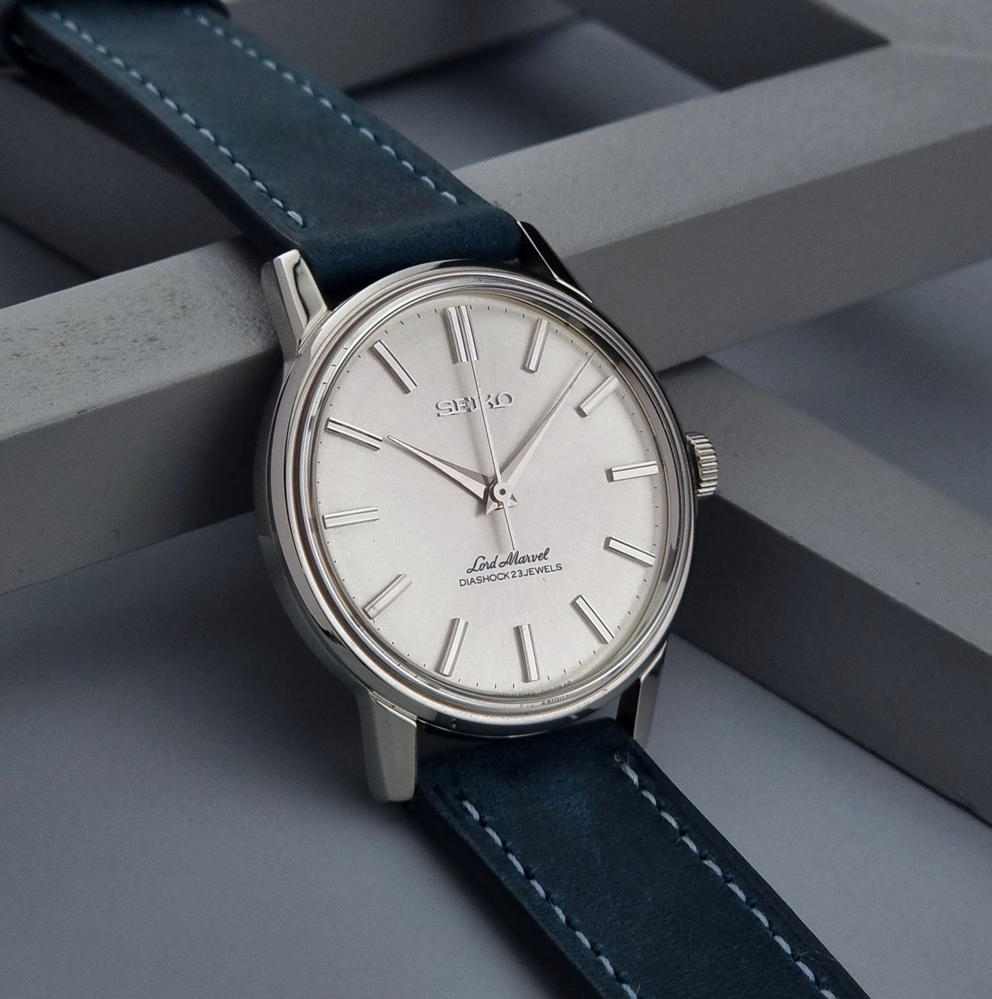 Seiko watch with blue leather strap on a gray geometric background