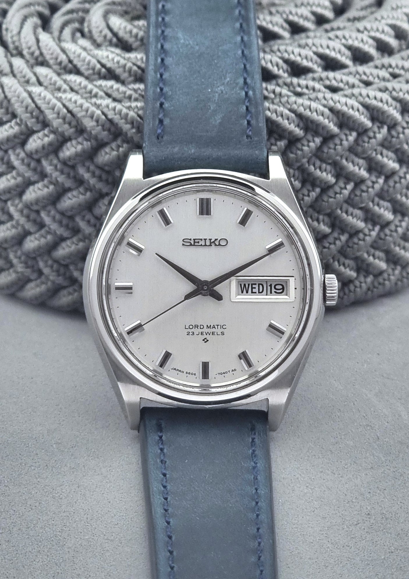 Vintage Seiko watch with blue leather strap on a textured gray background
