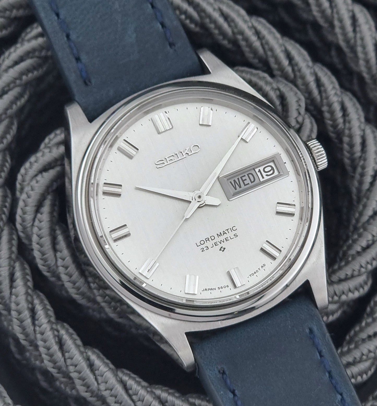 Vintage Seiko watch with blue strap on a textured gray background