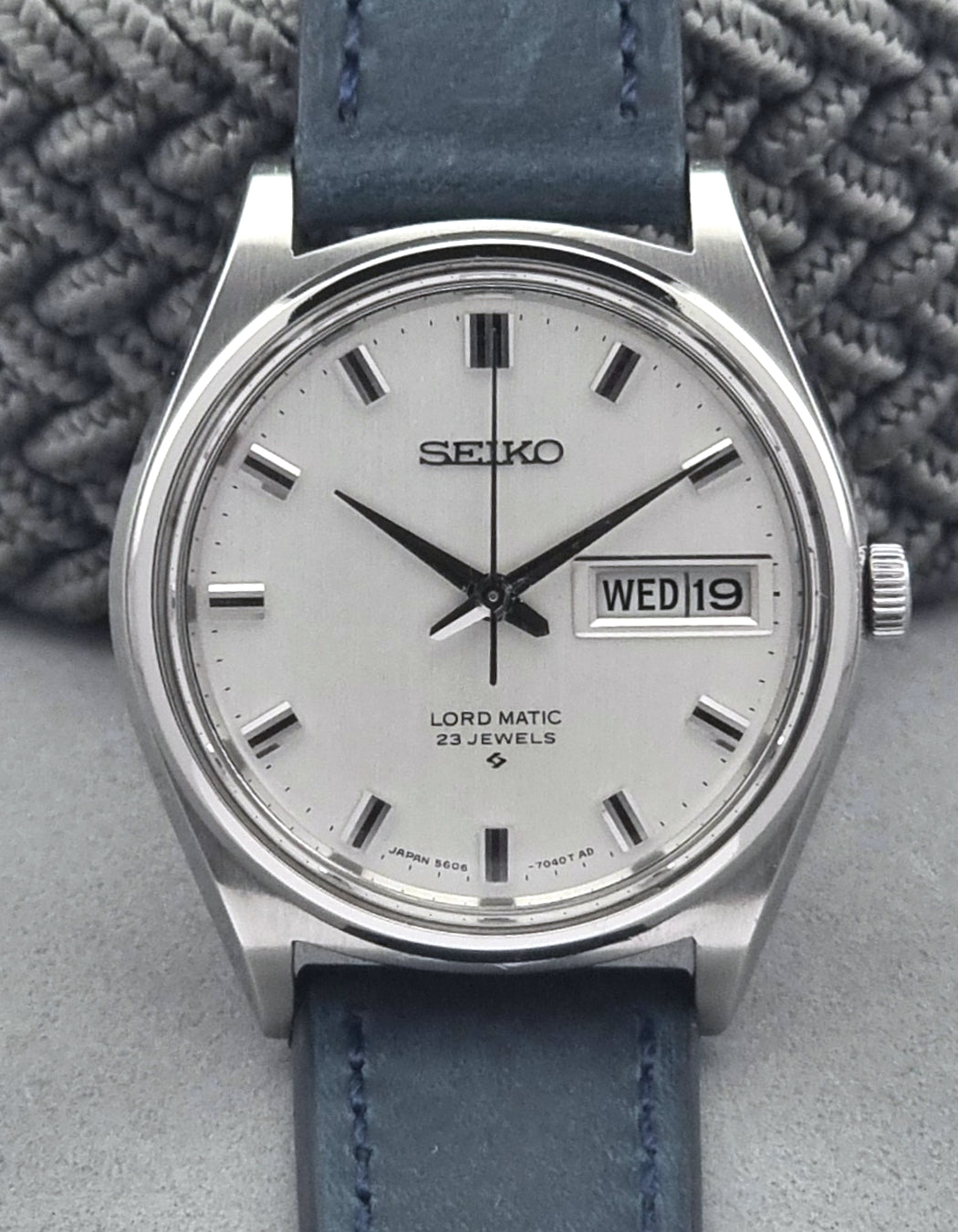 Vintage Seiko watch with blue leather strap on a textured gray background