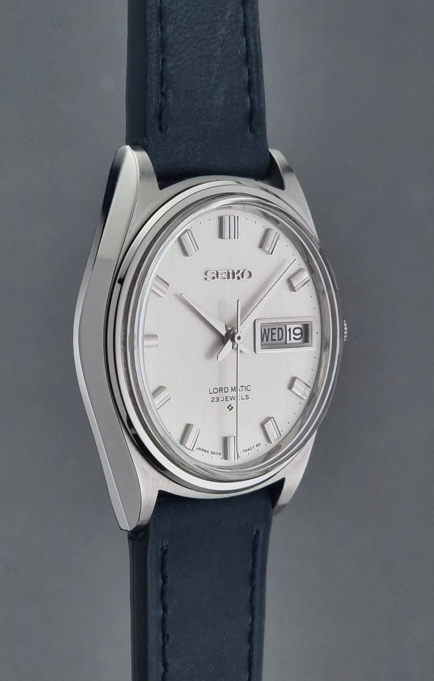 Seiko watch with a silver case and blue leather strap on a gray background