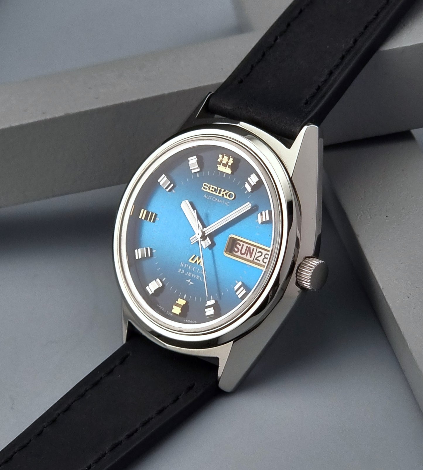 Vintage Seiko Lord Matic watch with black strap on a gray surface