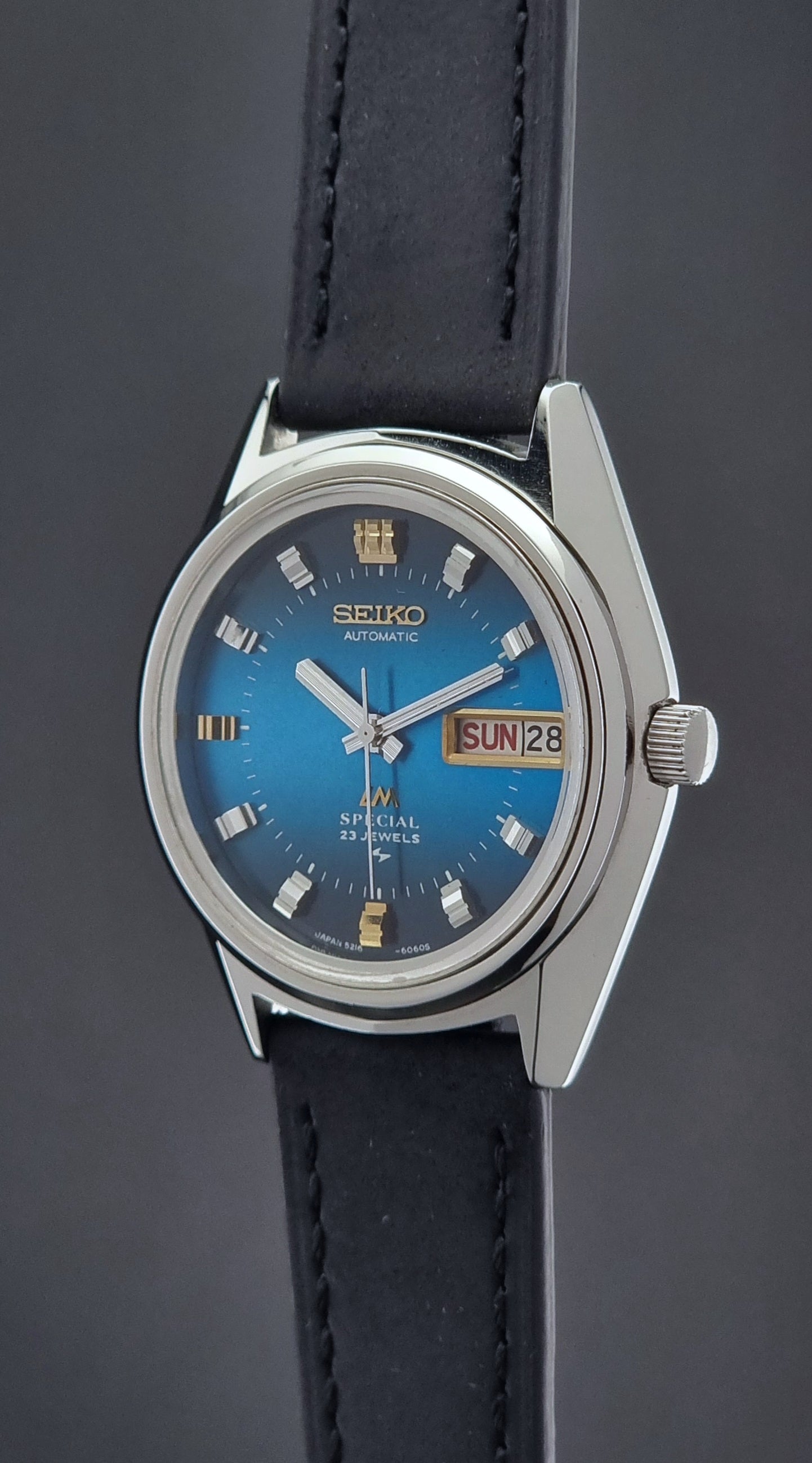 Vintage Seiko Lord Matic watch with blue face and black leather strap on a dark background