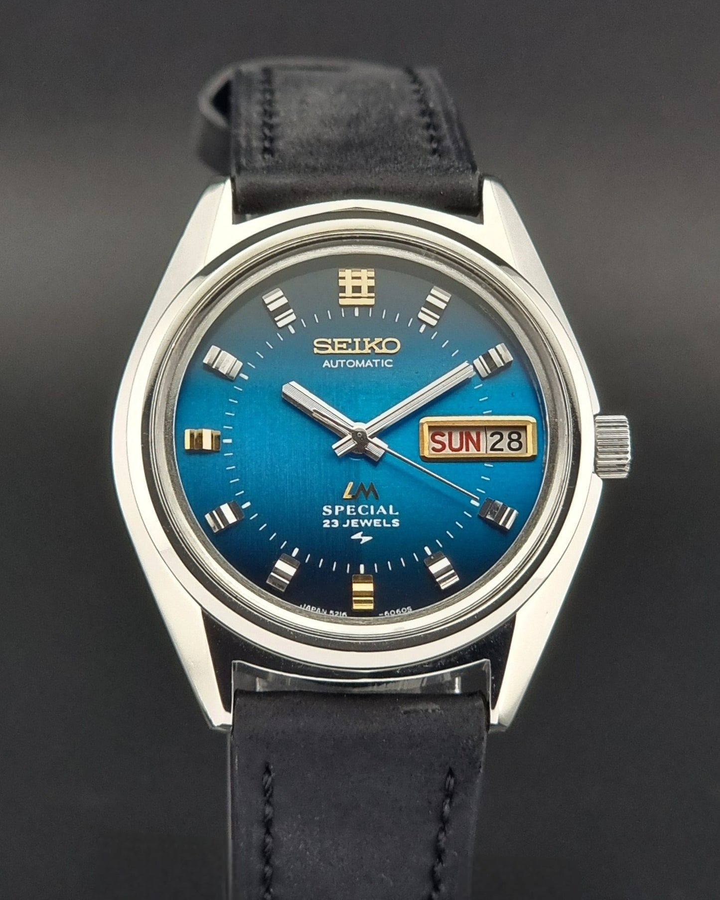 Vintage Seiko Lord Matic watch with blue dial and black leather strap on a dark background