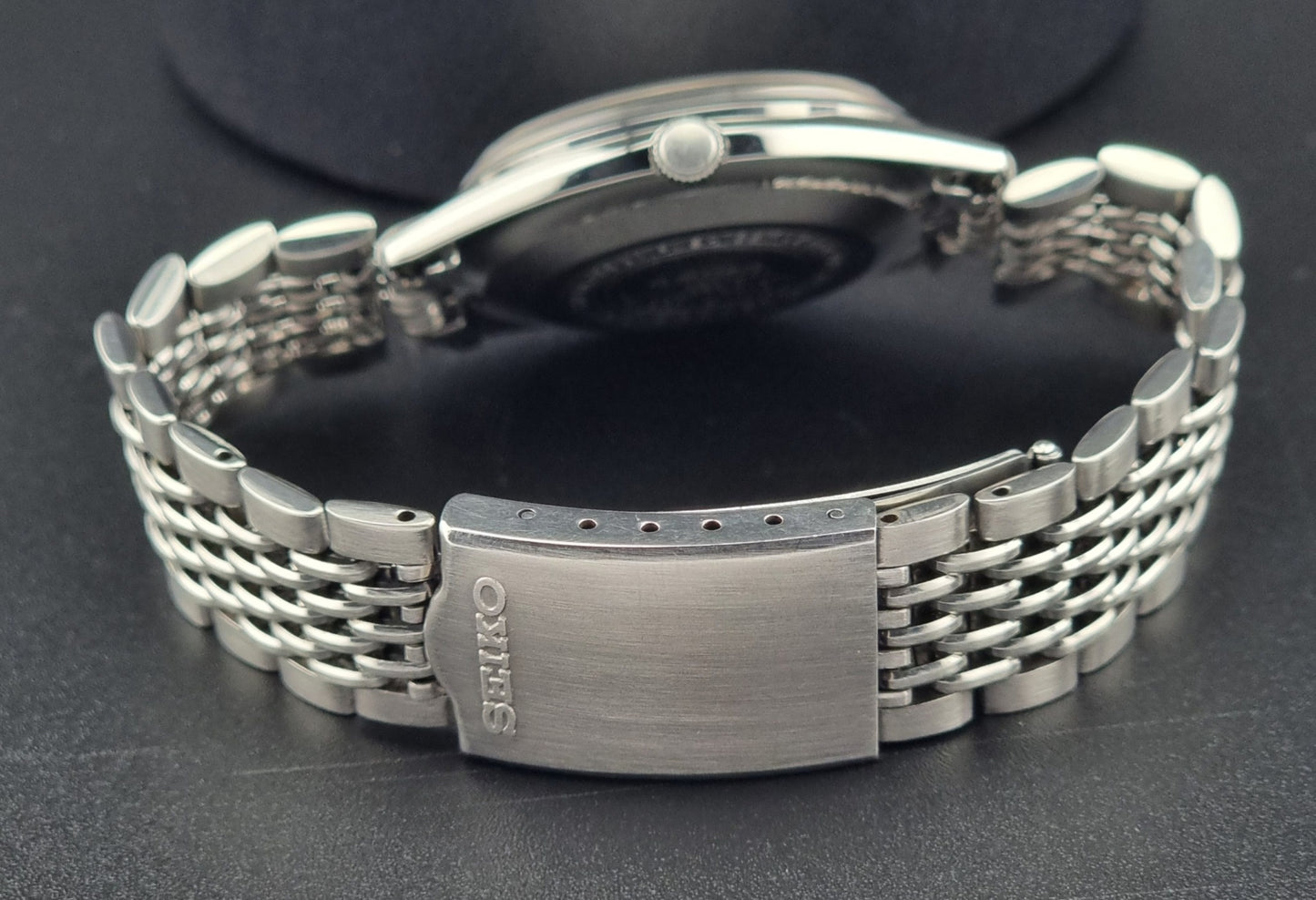 Silver Seiko watch case back on a dark background