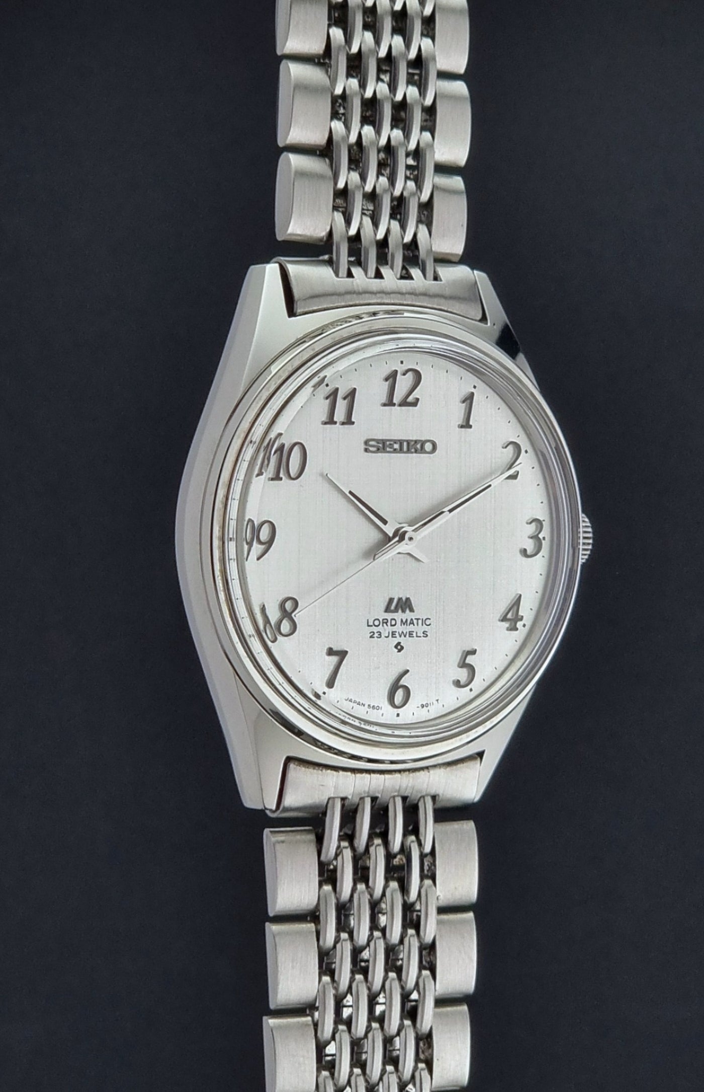 Silver Seiko Lord Matic watch with a chain strap on a black background