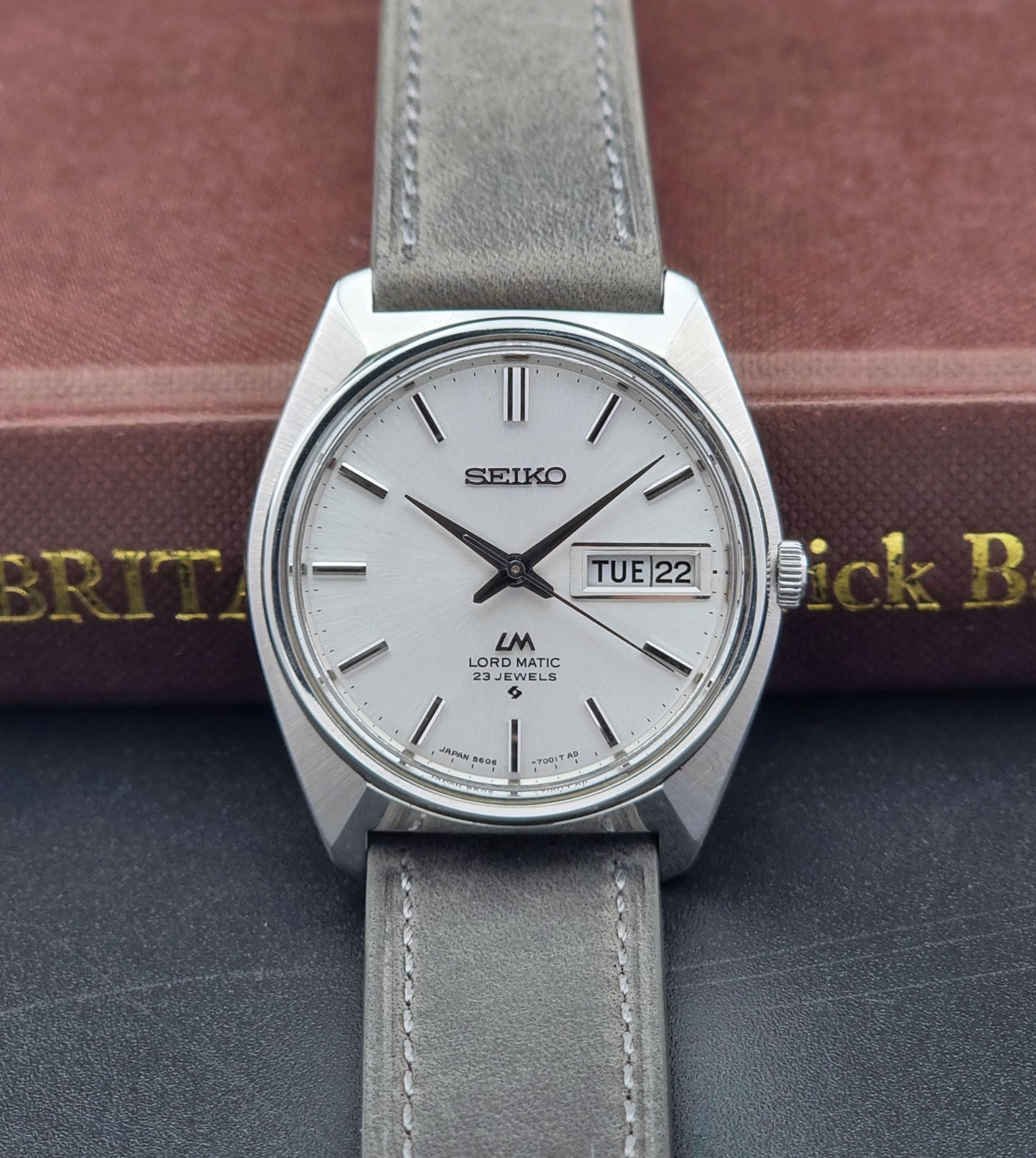 Vintage Seiko Wristwatch LordMatic 5606-7000 with gray strap on a dark surface front view