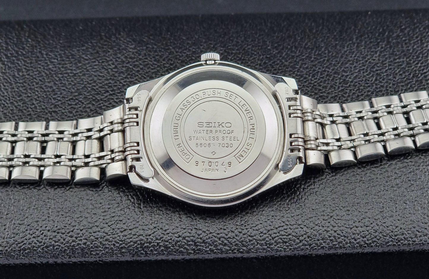 Close-up of a back view of a Seiko watch on a dark textured background