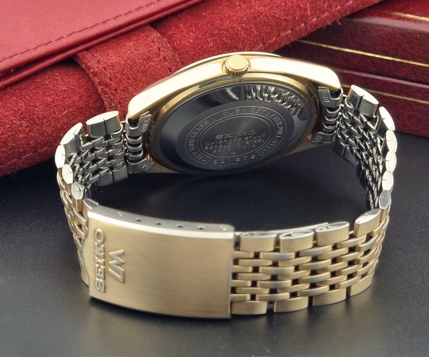 Vintage Seiko LordMatic 5606-7070 Gold wristwatch with a white face on a dark surface bracelet view