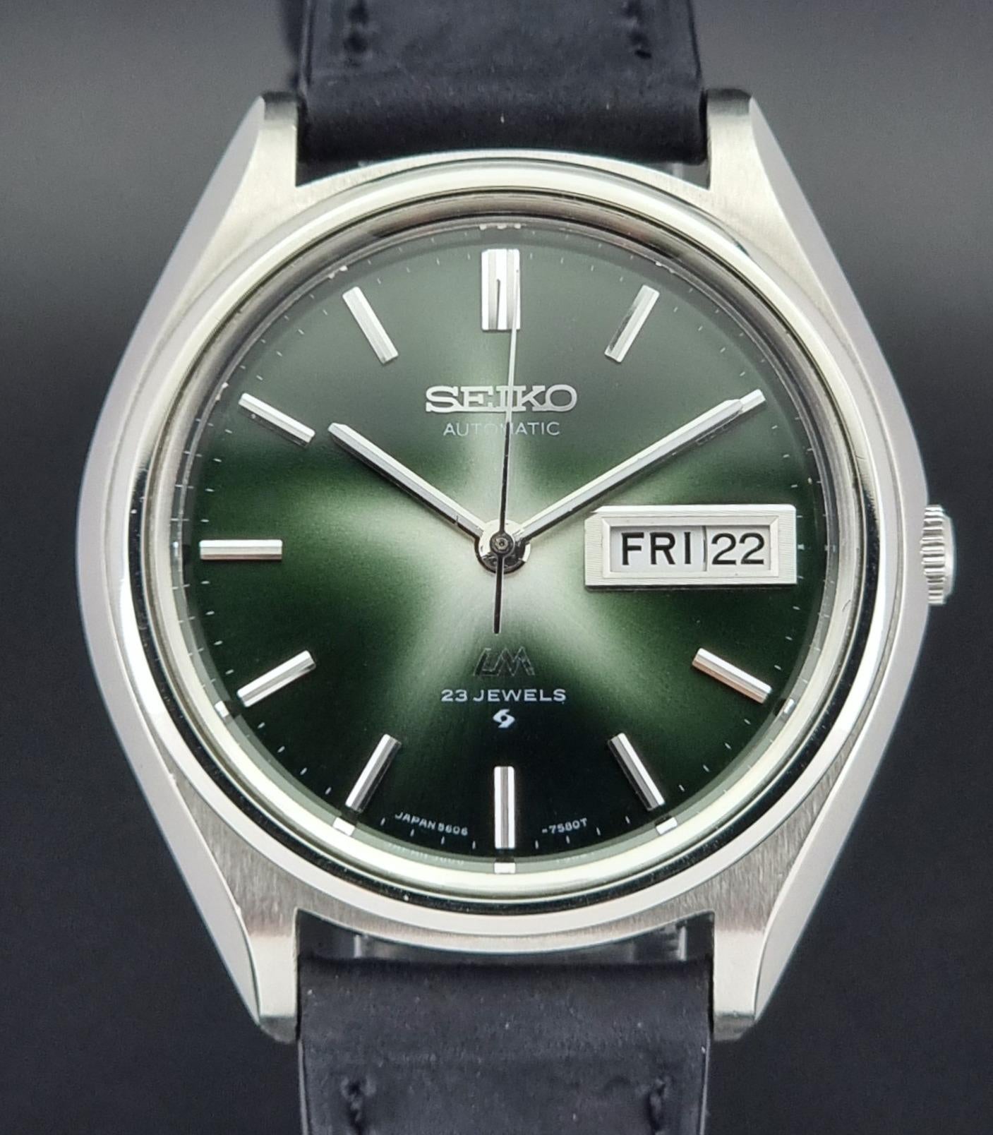 Seiko watch with green face and black leather strap on a dark background