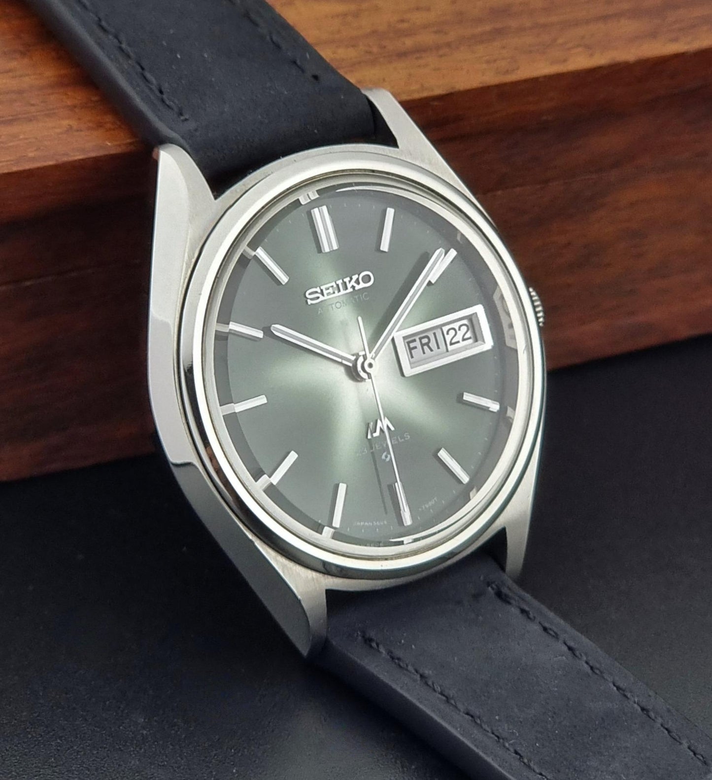 Vintage Seiko Lord Matic watch with black leather strap on a wooden surface