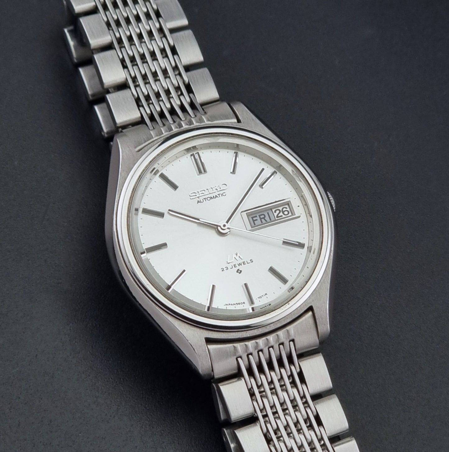 Vintage Seiko 5606-7071 watch LordMatic with a white dial and bracelet on a dark background front view