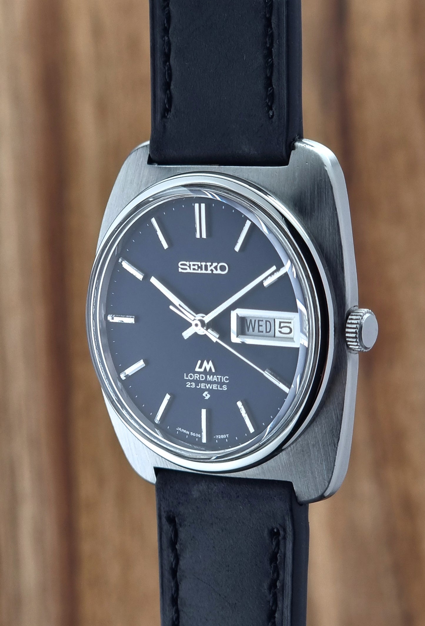Seiko watch with black leather strap on a wooden background