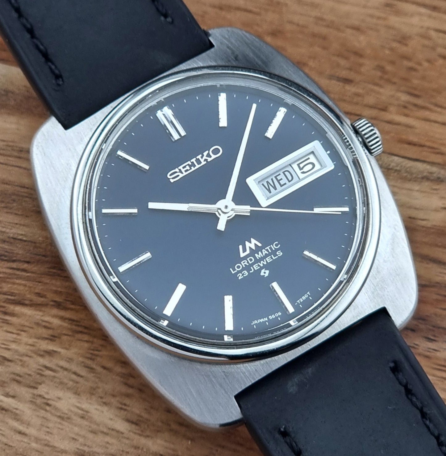 Seiko watch with black strap on a wooden surface