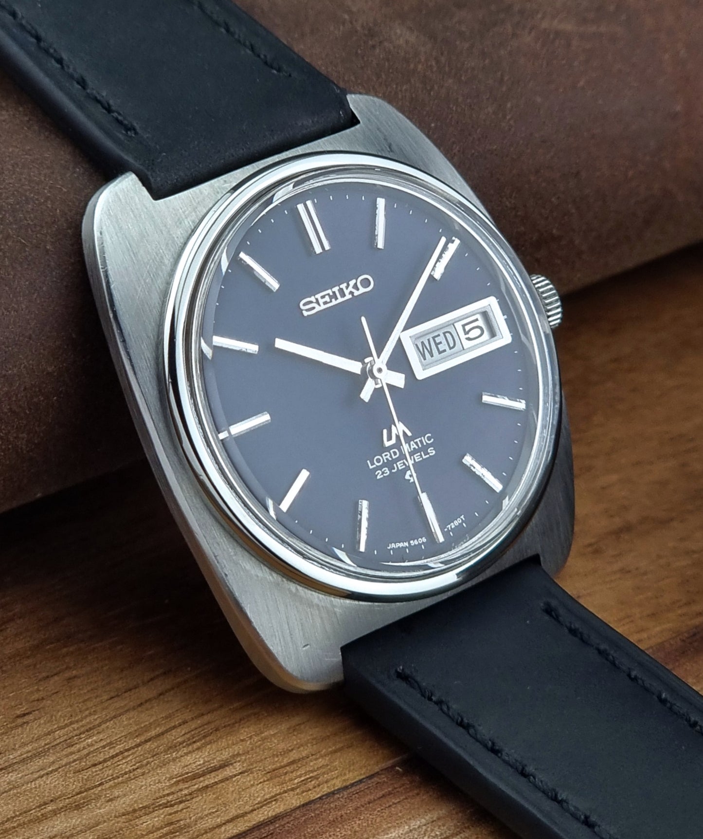 Seiko watch with black leather strap on a wooden surface