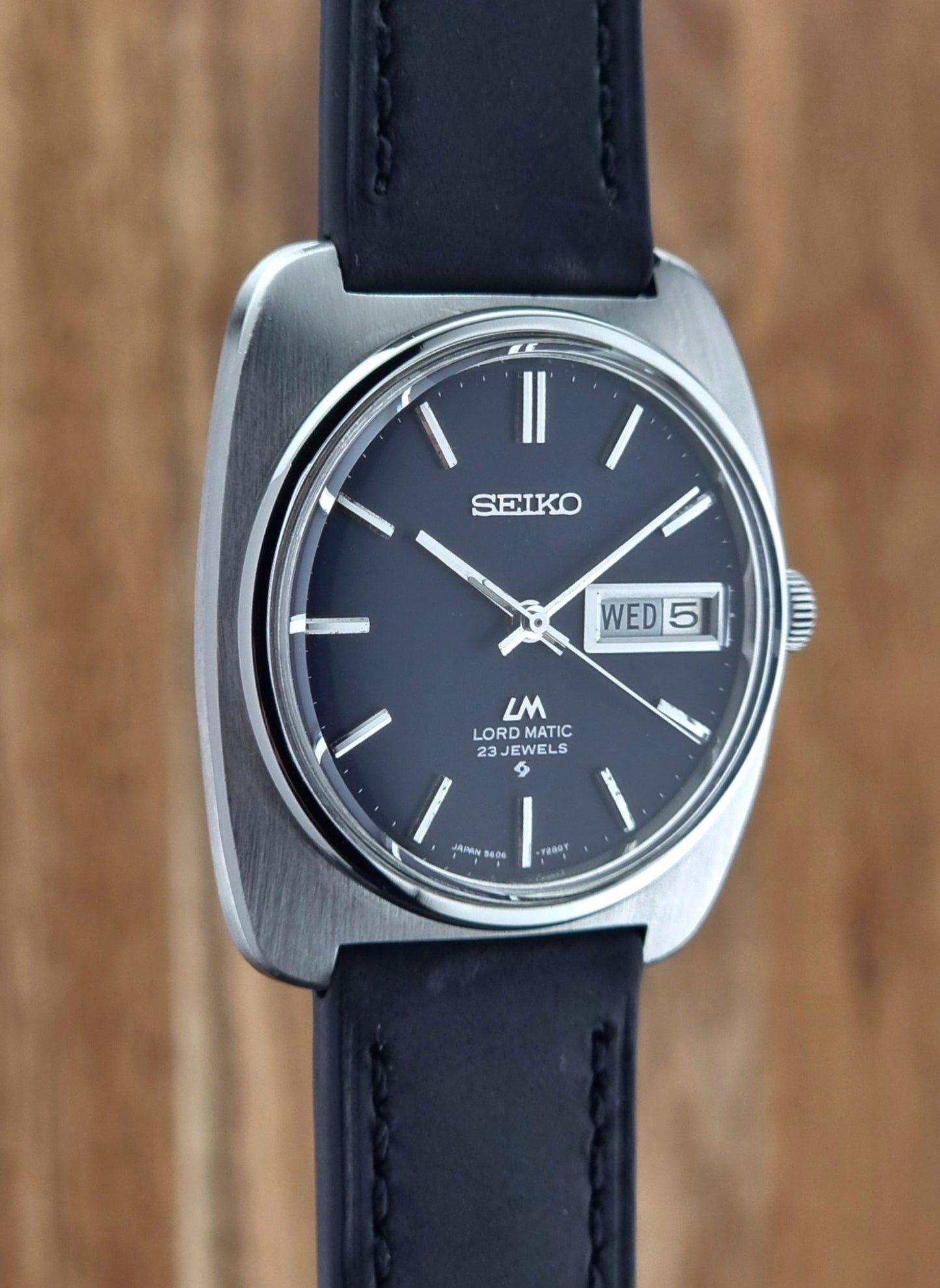 Seiko watch with black leather strap on a wooden background