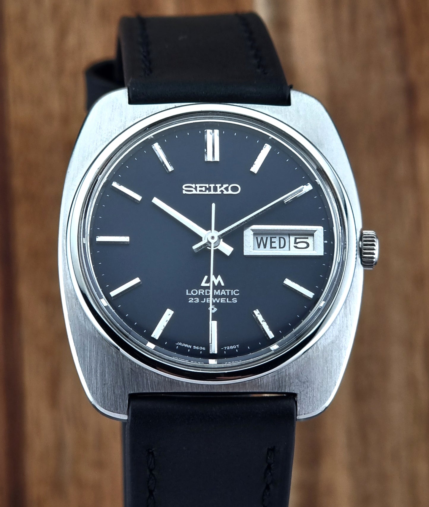 Seiko watch with black leather strap on a wooden background
