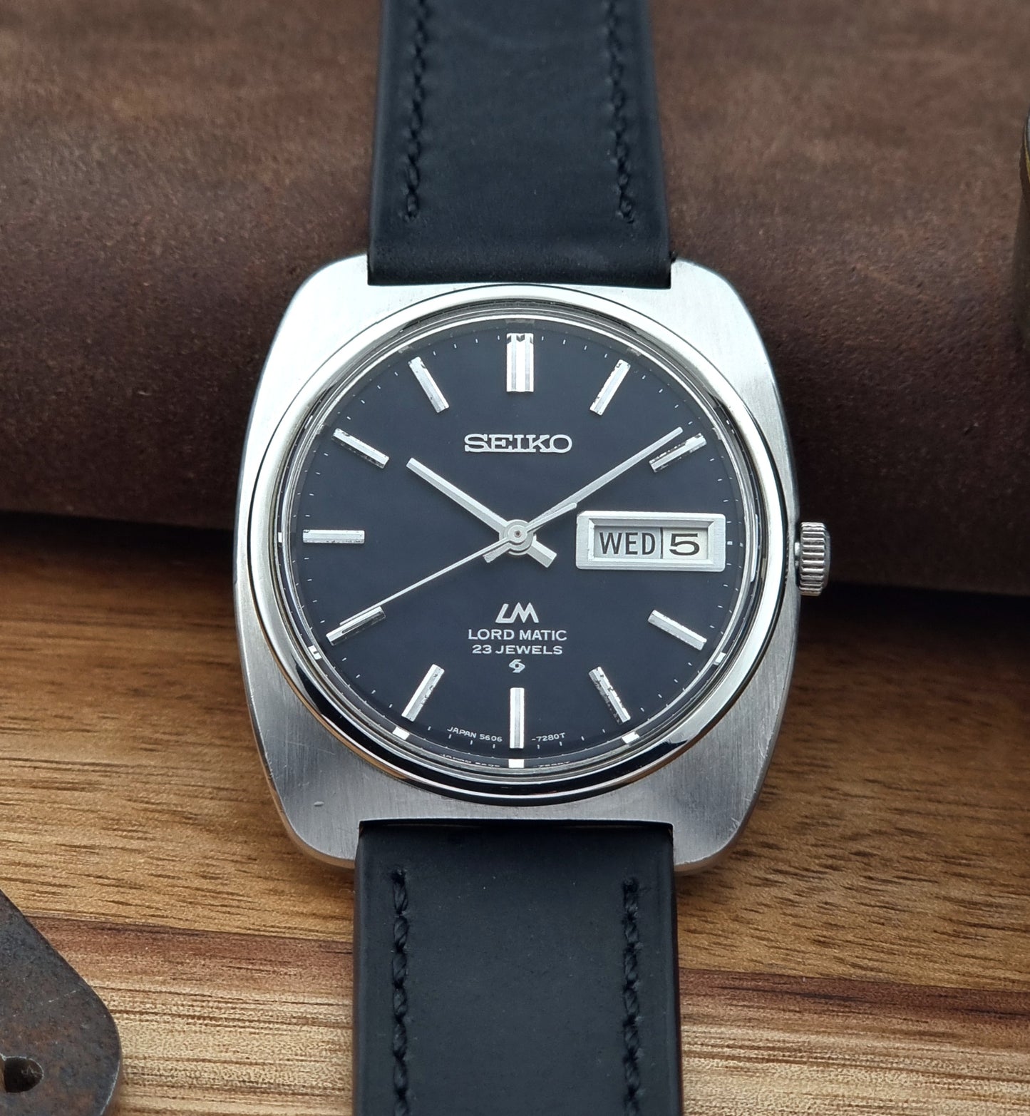 Seiko watch with black leather strap on a wooden surface