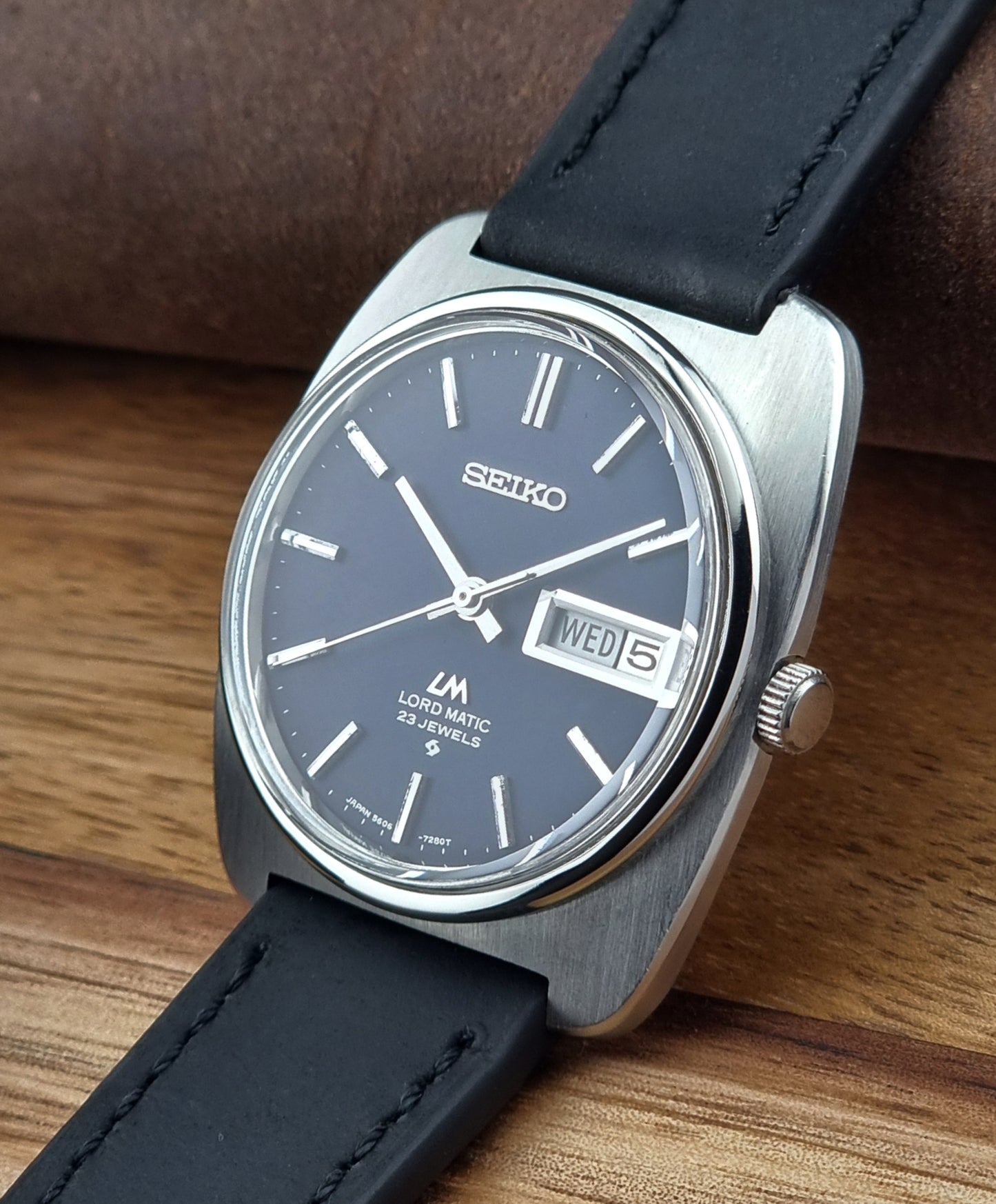 Seiko watch with black leather strap on a wooden surface