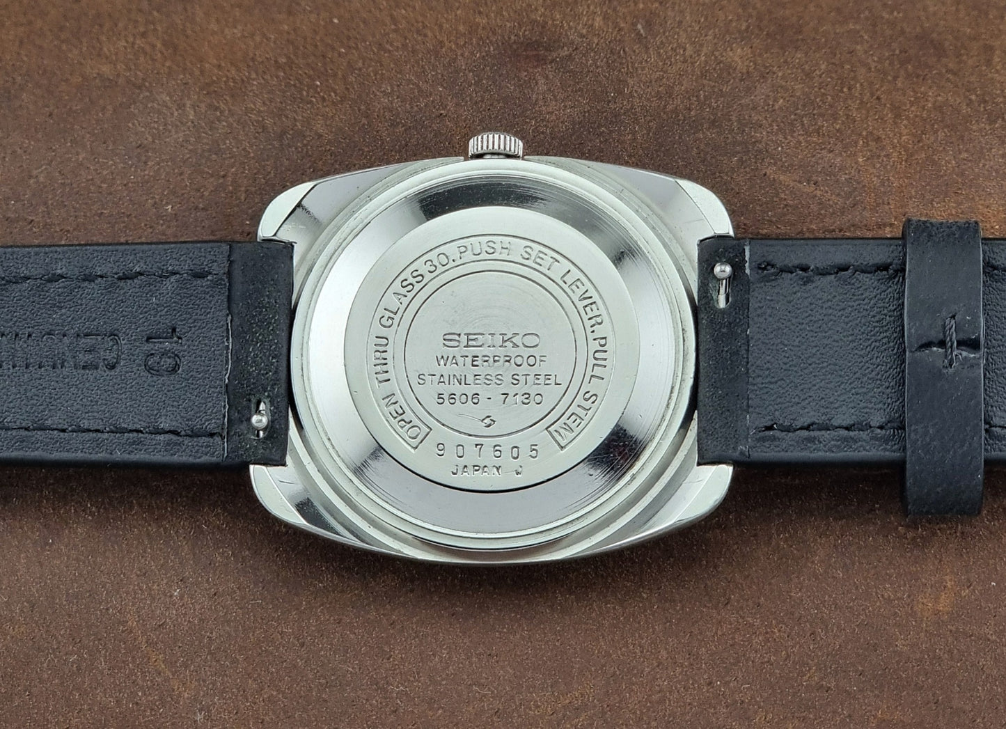 Seiko watch back on a brown leather background