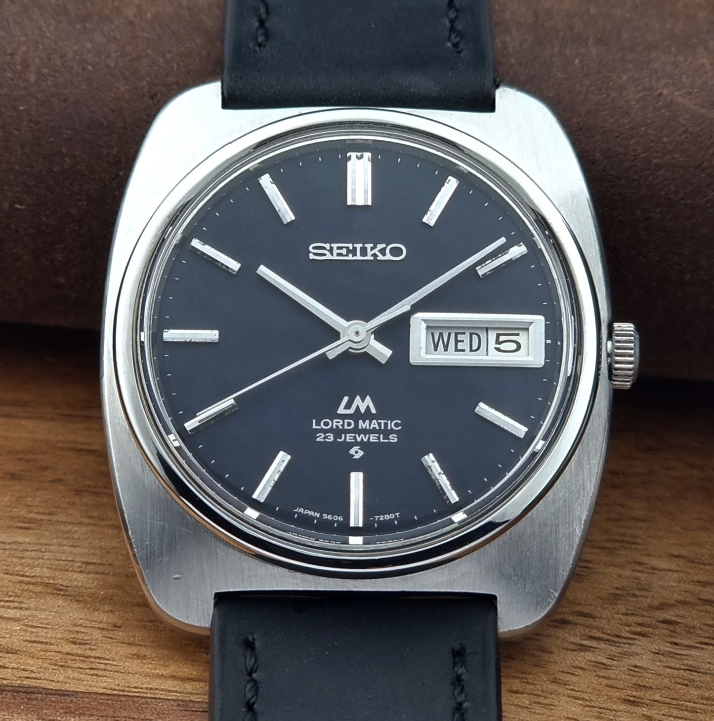 Seiko watch with black leather strap on a wooden surface