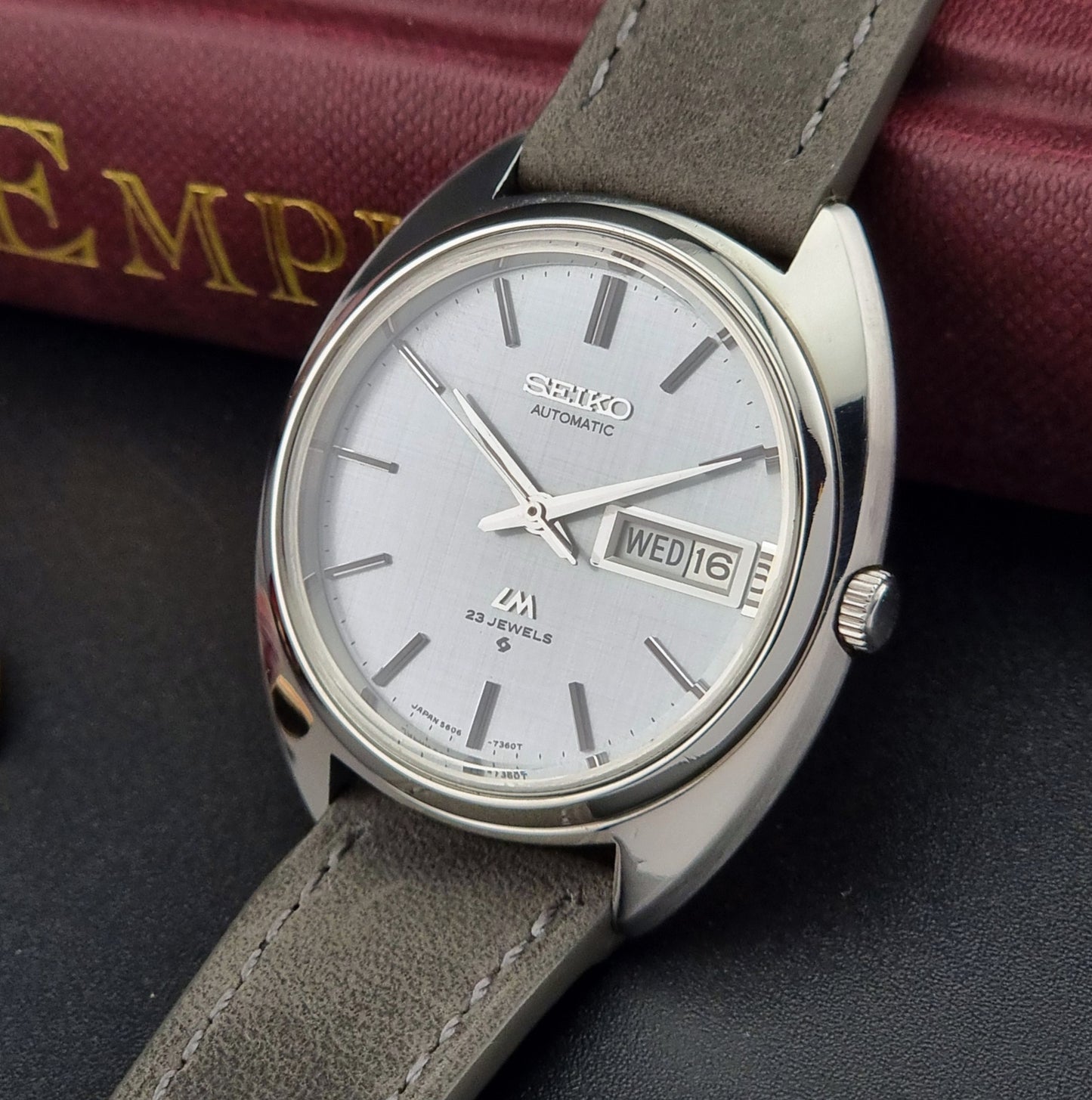 Seiko watch with gray strap on a dark surface